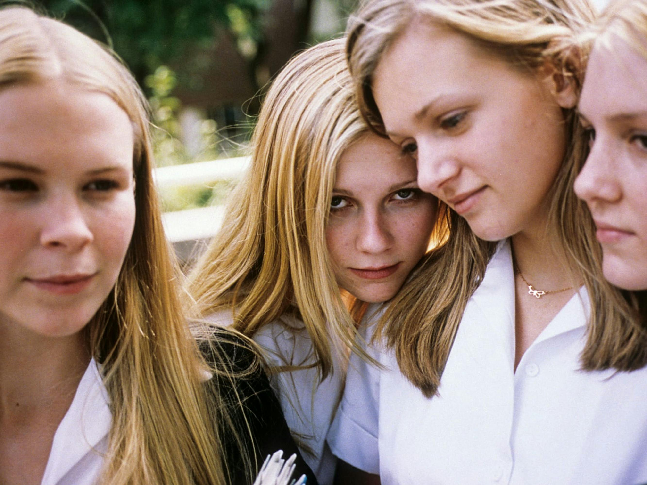 Therese Lisbon (Leslie Hayman), Lux Lisbon (Kirsten Dunst), Mary Lisbon (A.J. Cook), and Bonnie Lisbon (Chelse Swain) stand close together wearing white shirts.