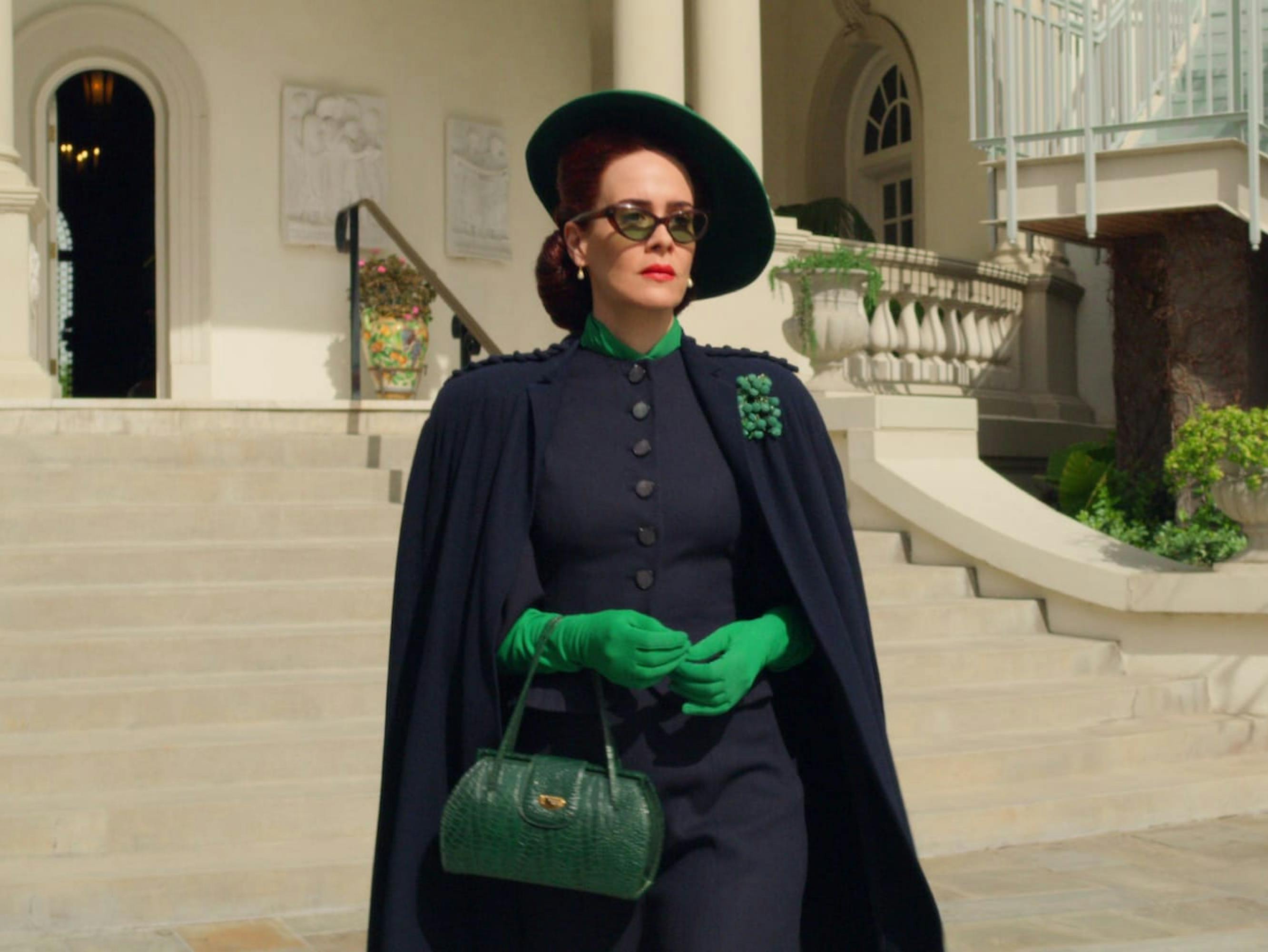 Nurse Mildred Ratched (Sarah Paulson) wears a black ensemble trimmed with green, reminiscent of the wicked witch of the west. Her green bag, color, and gloves allude to nefarious activity.