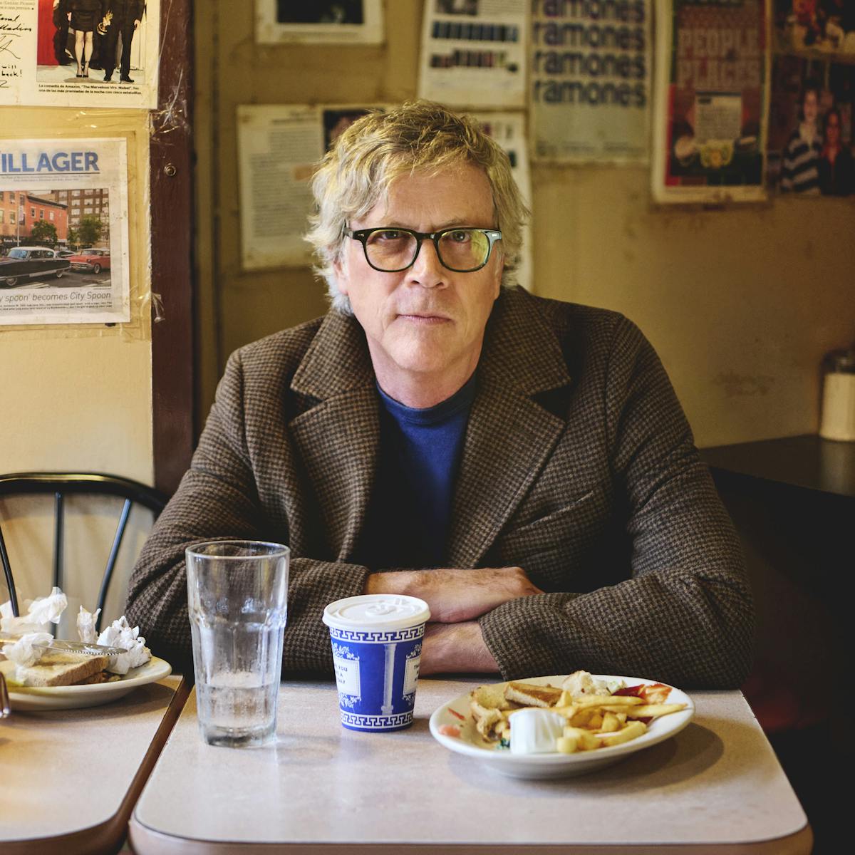 Todd Haynes sits at a diner table drinking coffee and water and eating fries.