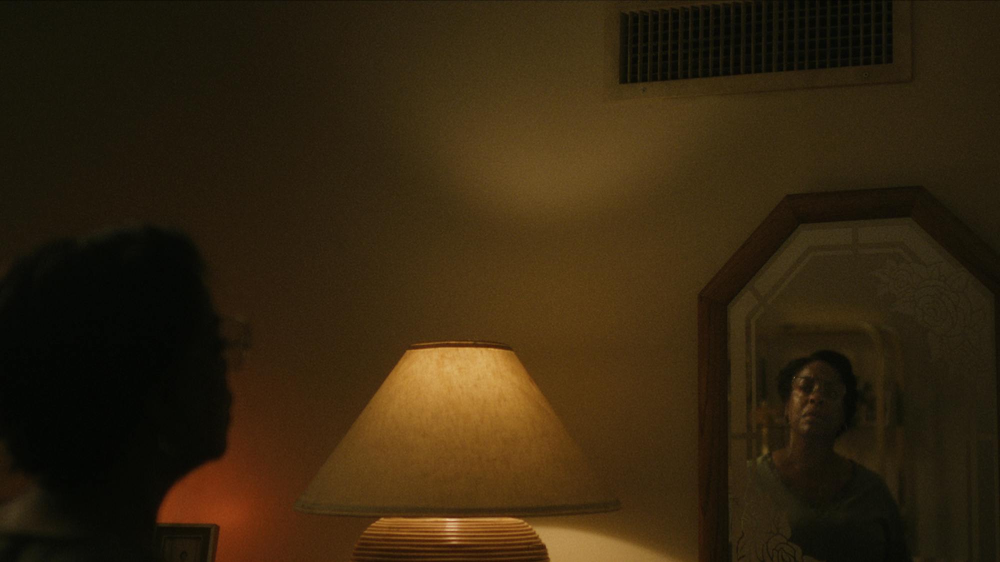 Glenda Cleveland (Niecy Nash) looks into a dimly-lit mirror.