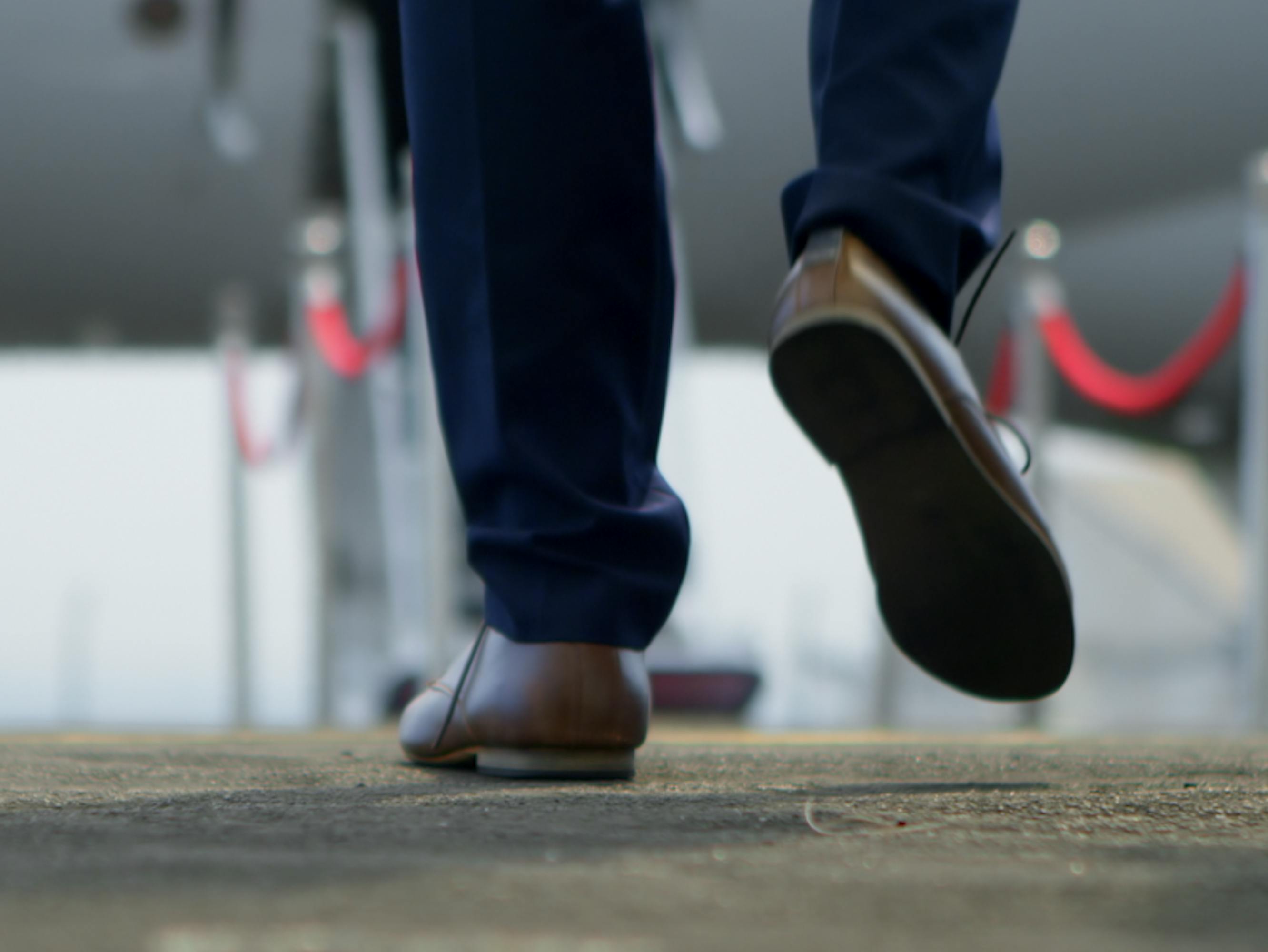 A man walking in new loafers towards a private plane.