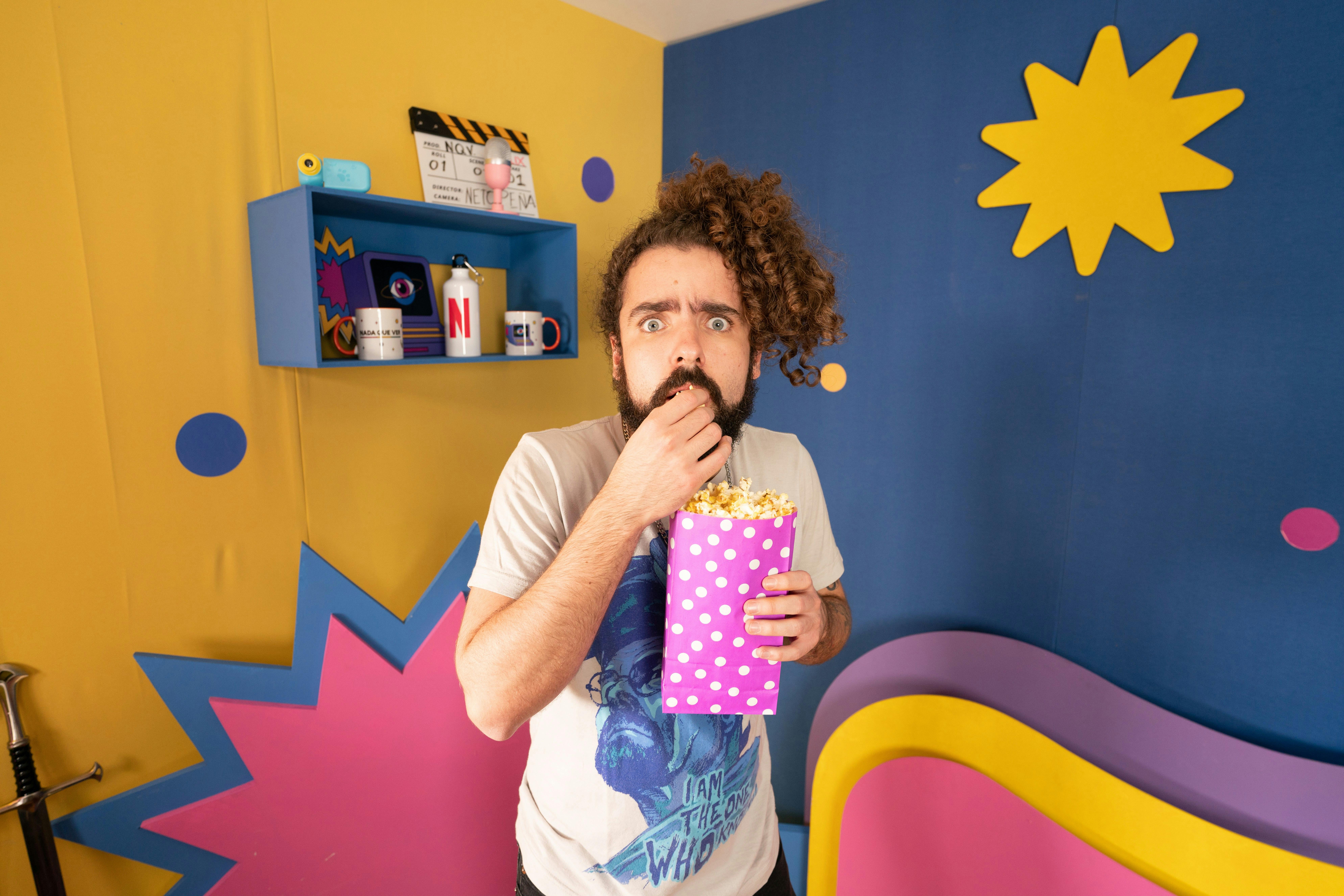 Javier Ibarreche eats popcorn in a colorful room. 