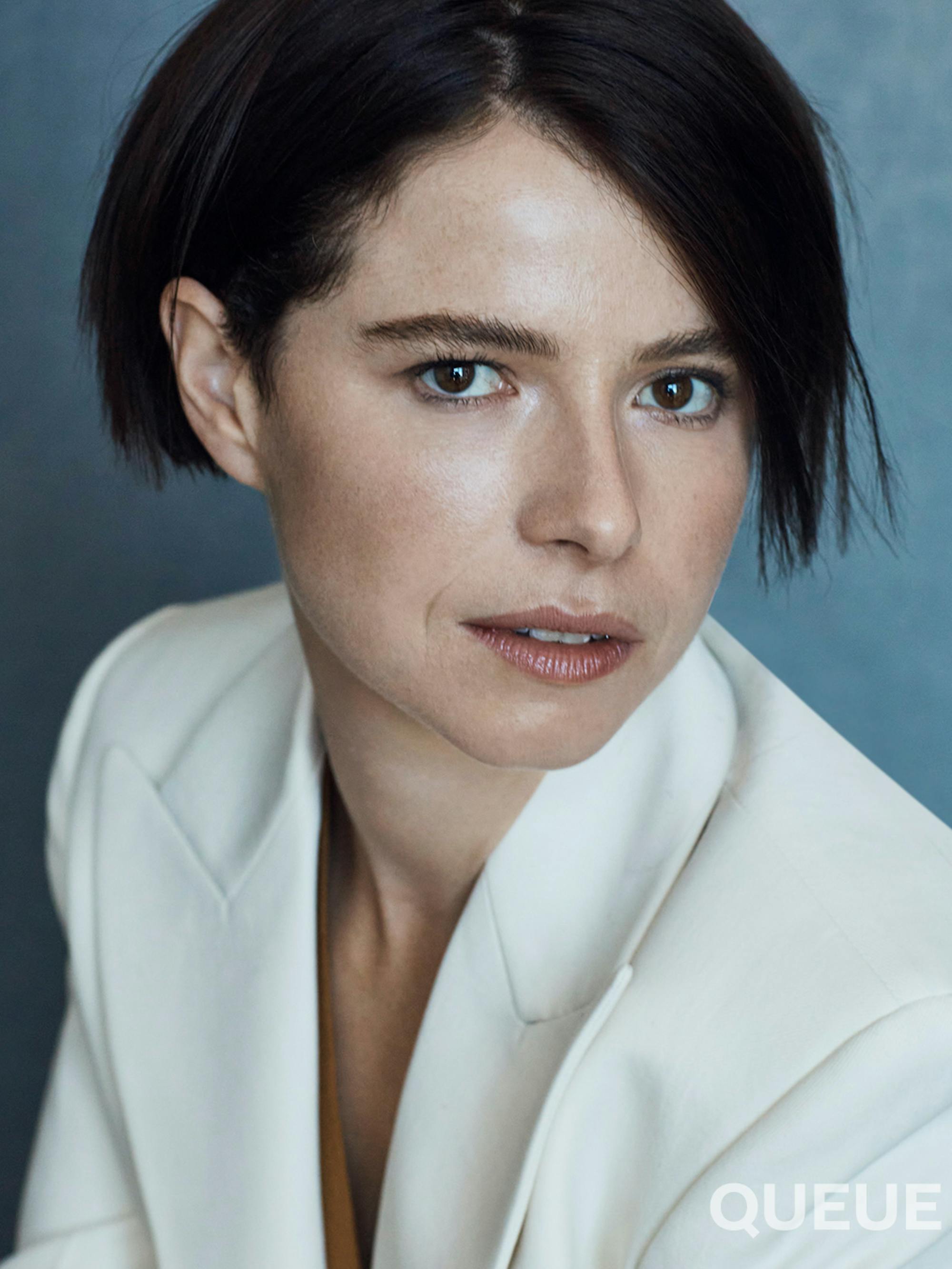 Jessie Buckley wears a white blazer.