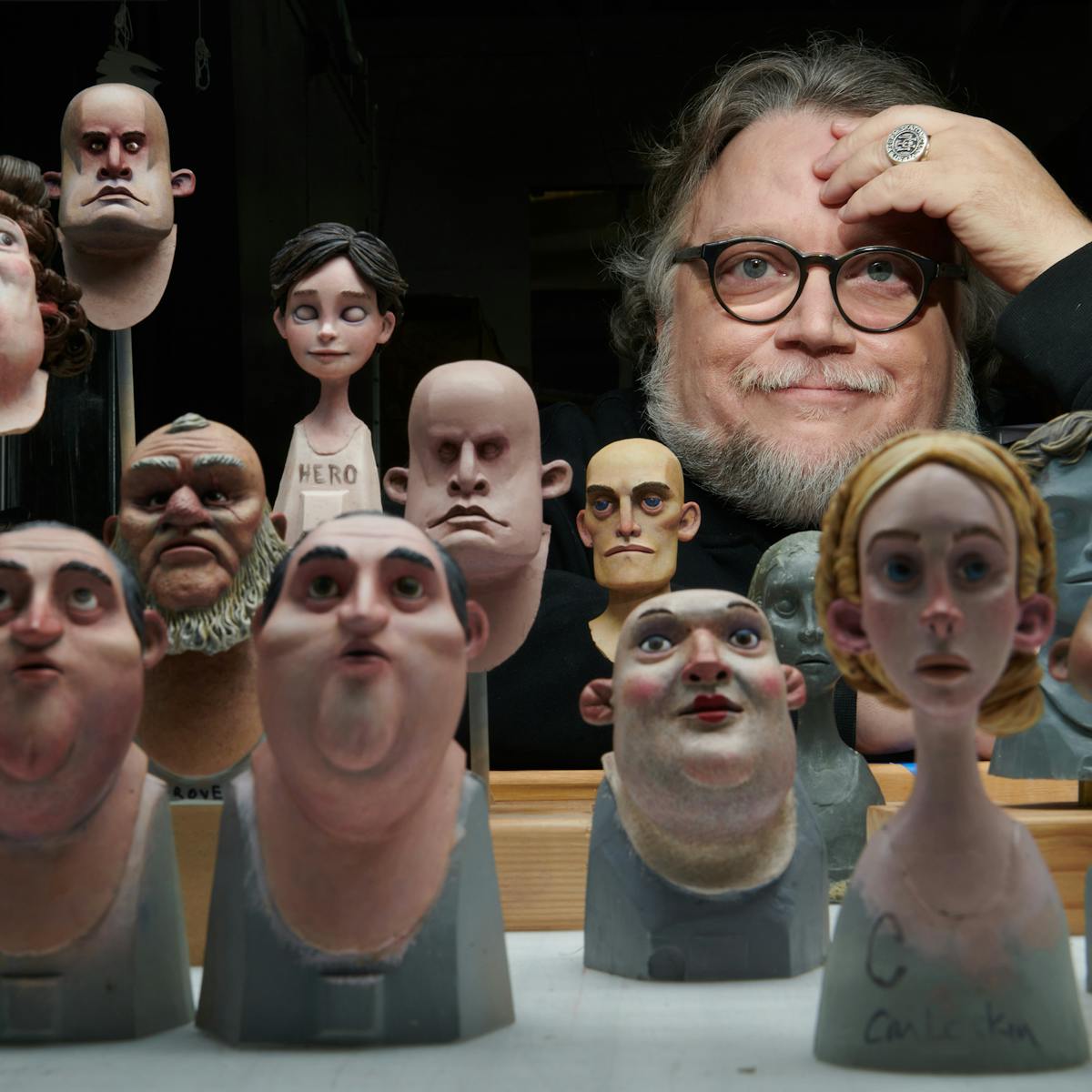 Guillermo del Toro looks at the camera through a crowd of puppets.