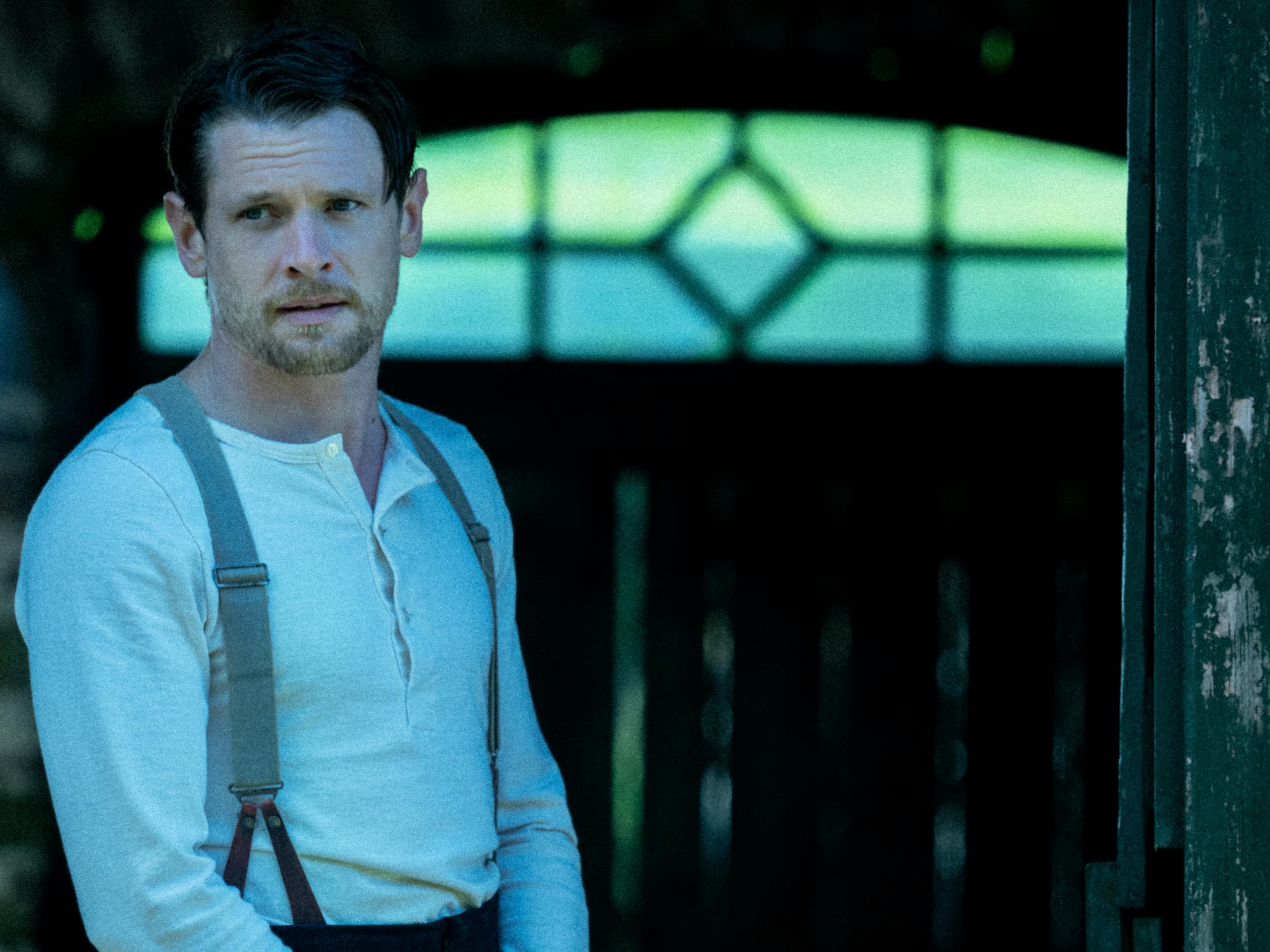 Oliver Mellors (Jack O'Connell) wears a white shirt and suspenders.