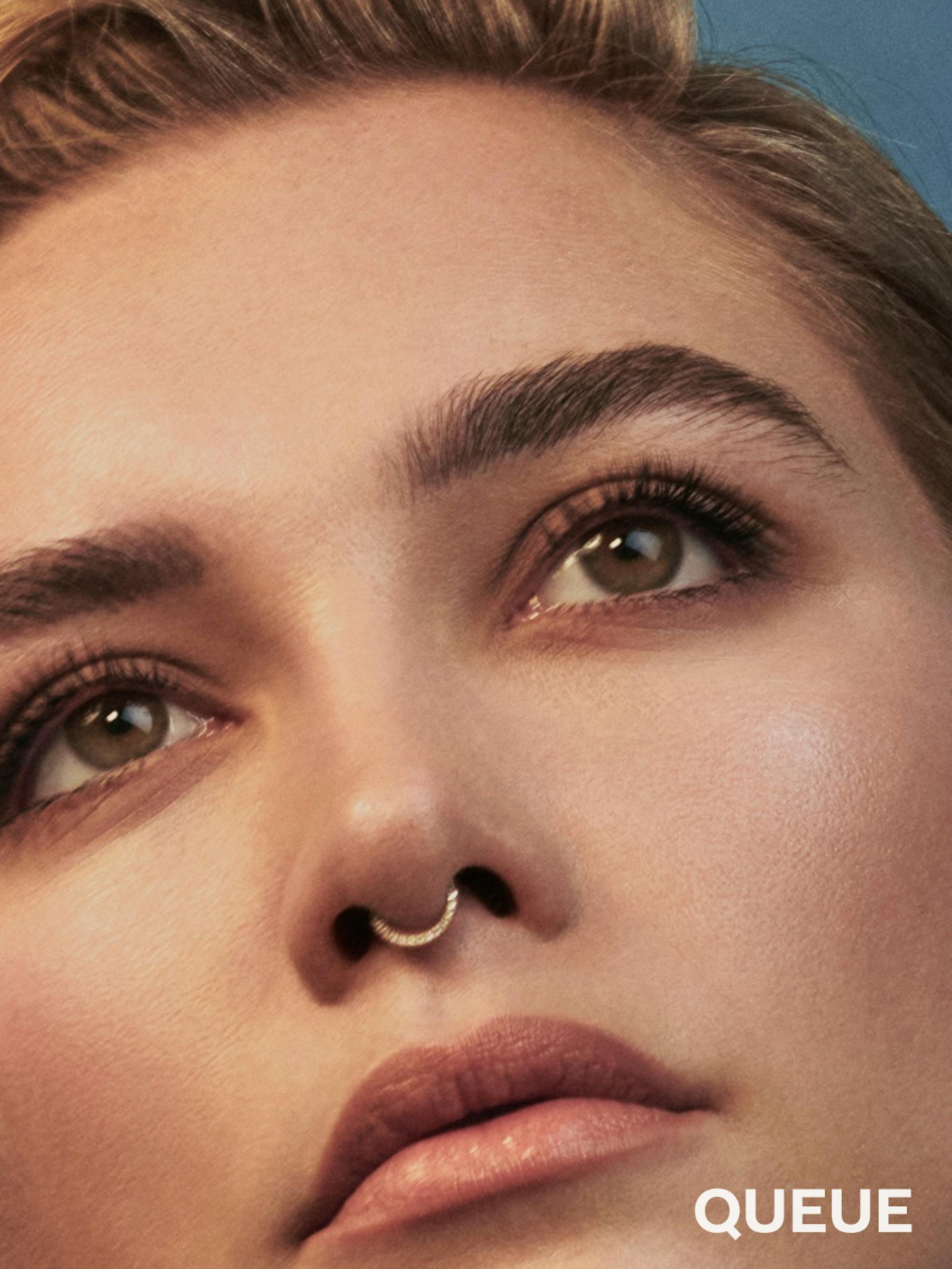Florence Pugh wears a nose ring and looks offscreen.