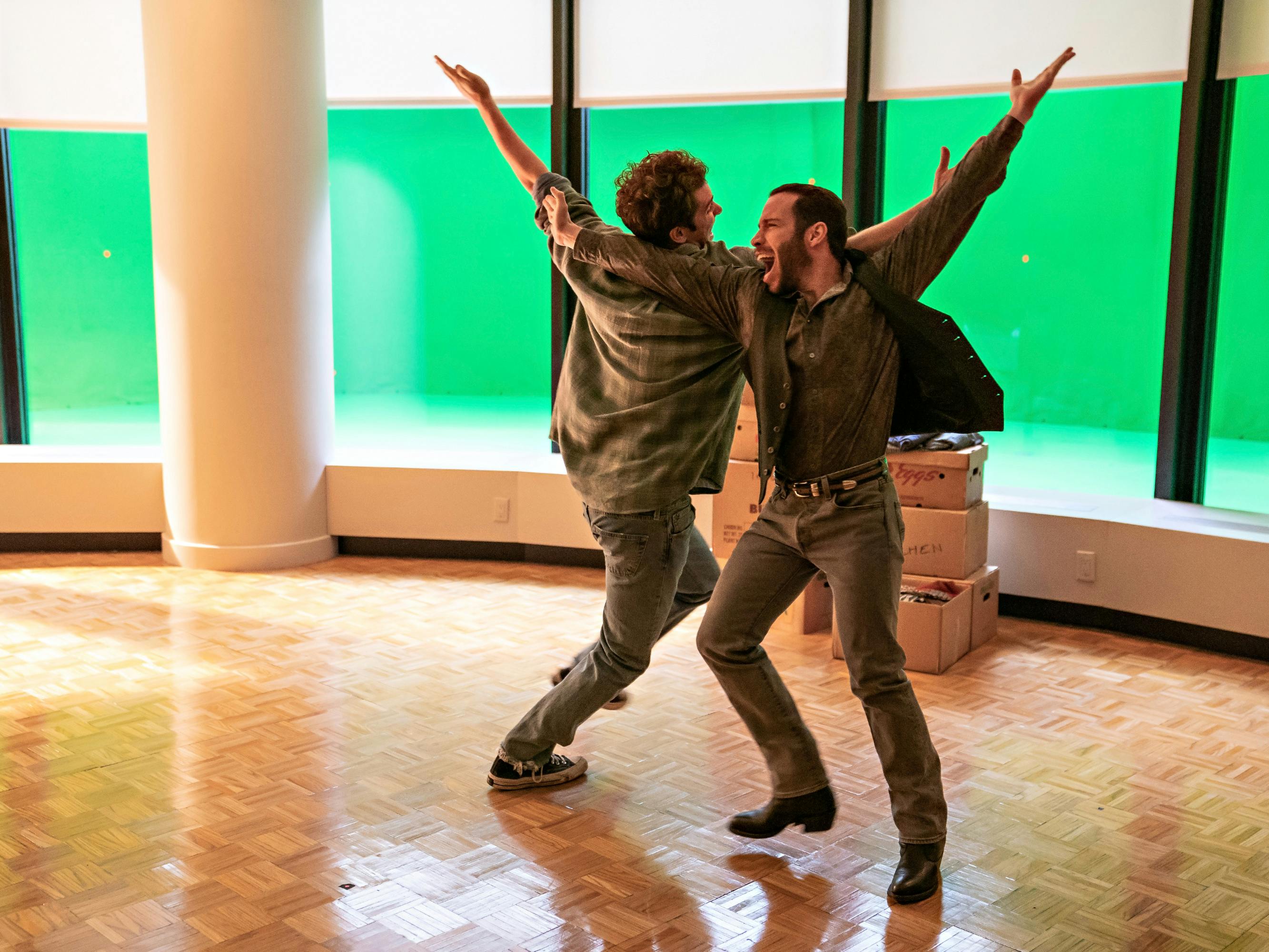 Andrew Garfield and Robin de Jesús dance in a sunlit wood dance studio.