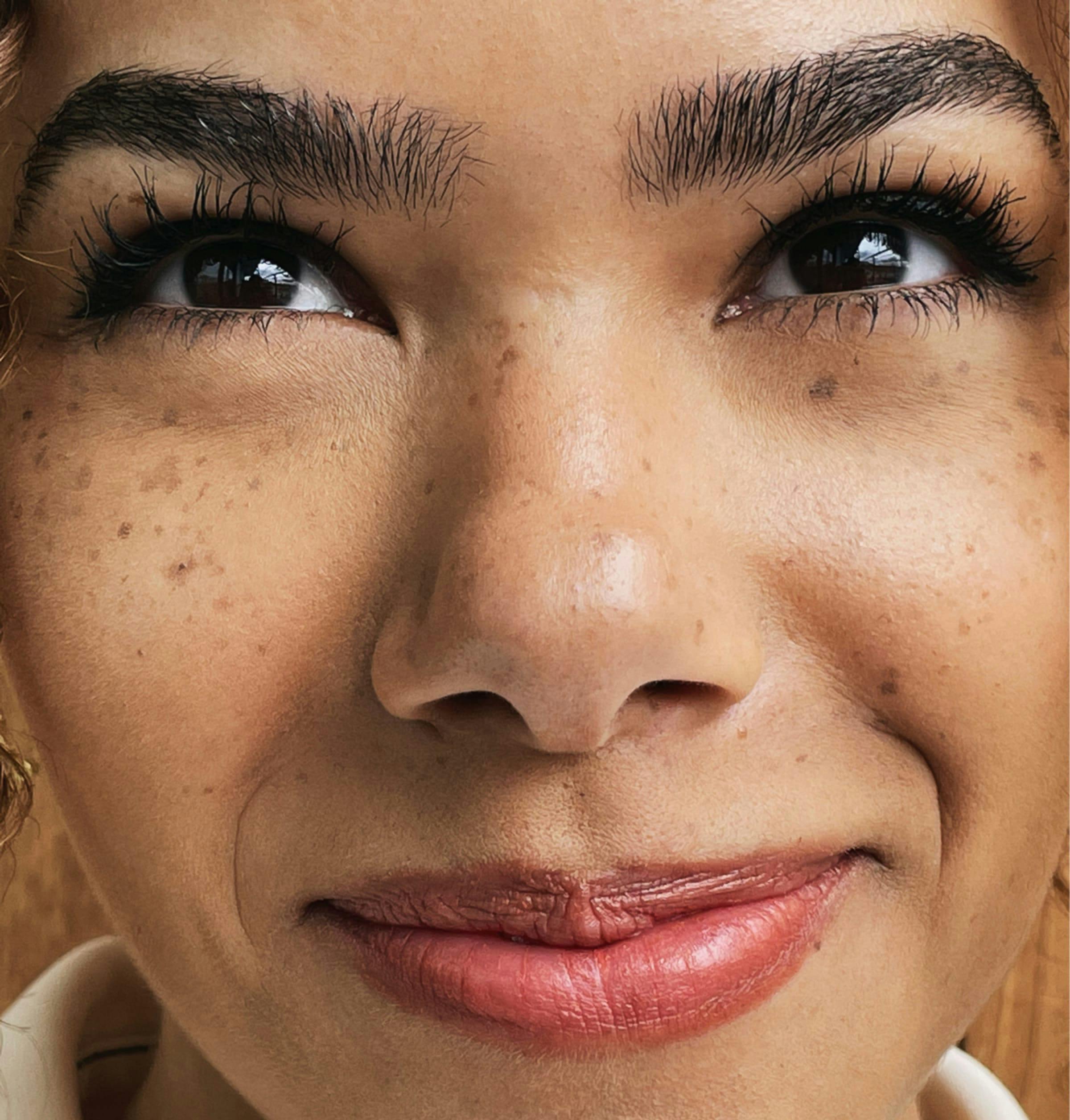 A closeup shot of Antonia Gentry. She has a very lovely smile, upturned brown eyes, impeccable eyebrows, and some freckles across her cheeks.