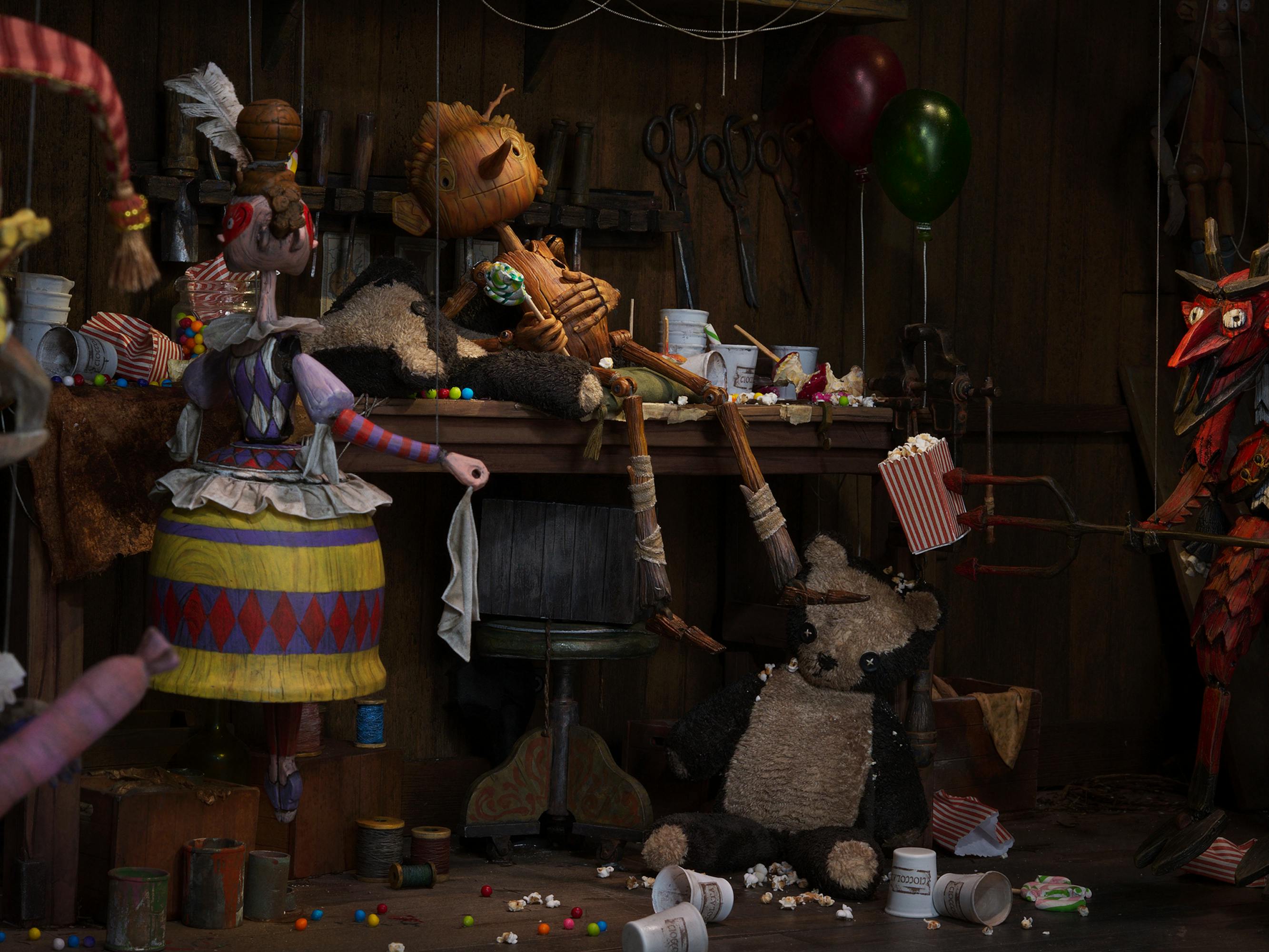 Pinocchio (Gregory Mann) rests on a worktable after eating some sweet treats and snacks.