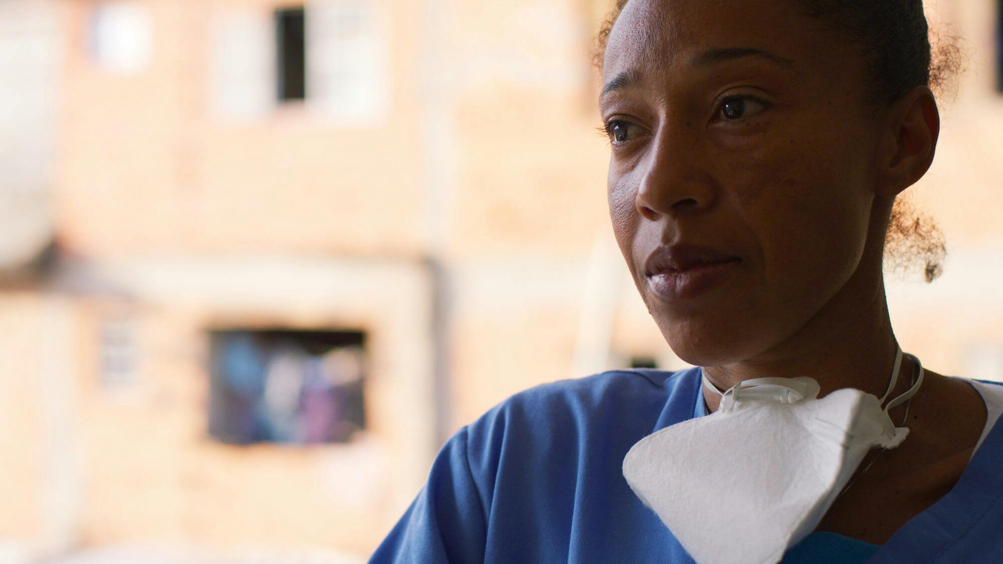 Renata Alves wears a mask around her neck and blue scrubs.