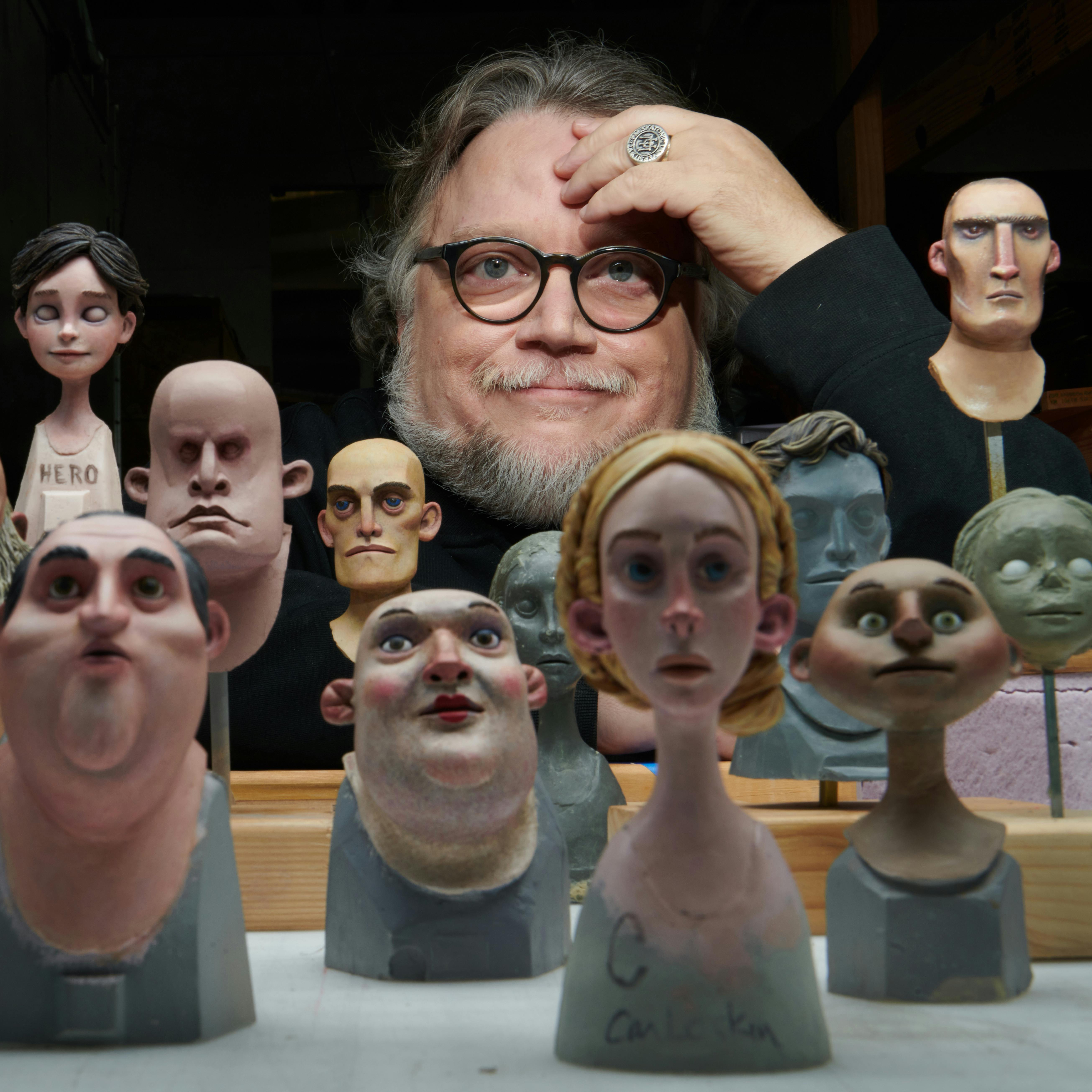 Guillermo del Toro looks at the camera through a crowd of puppets.