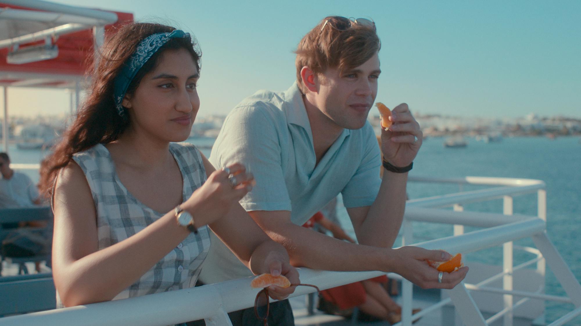 Emma Morley (Ambika Mod) and Dexter Mayhew (Leo Woodall) share an orange and they lean off the edge of a boat, enjoying the view.