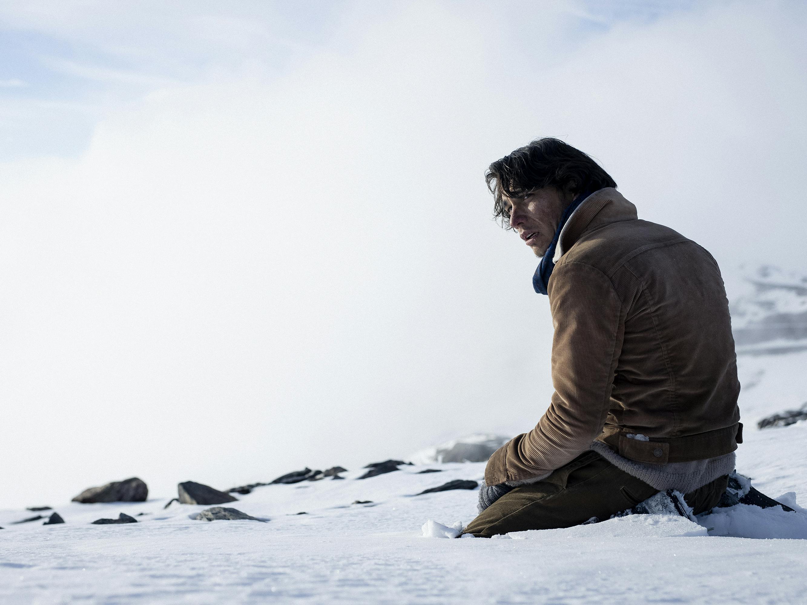 Numa (Enzo Vogrincic) wears a brown jacket and kneels in the snow.