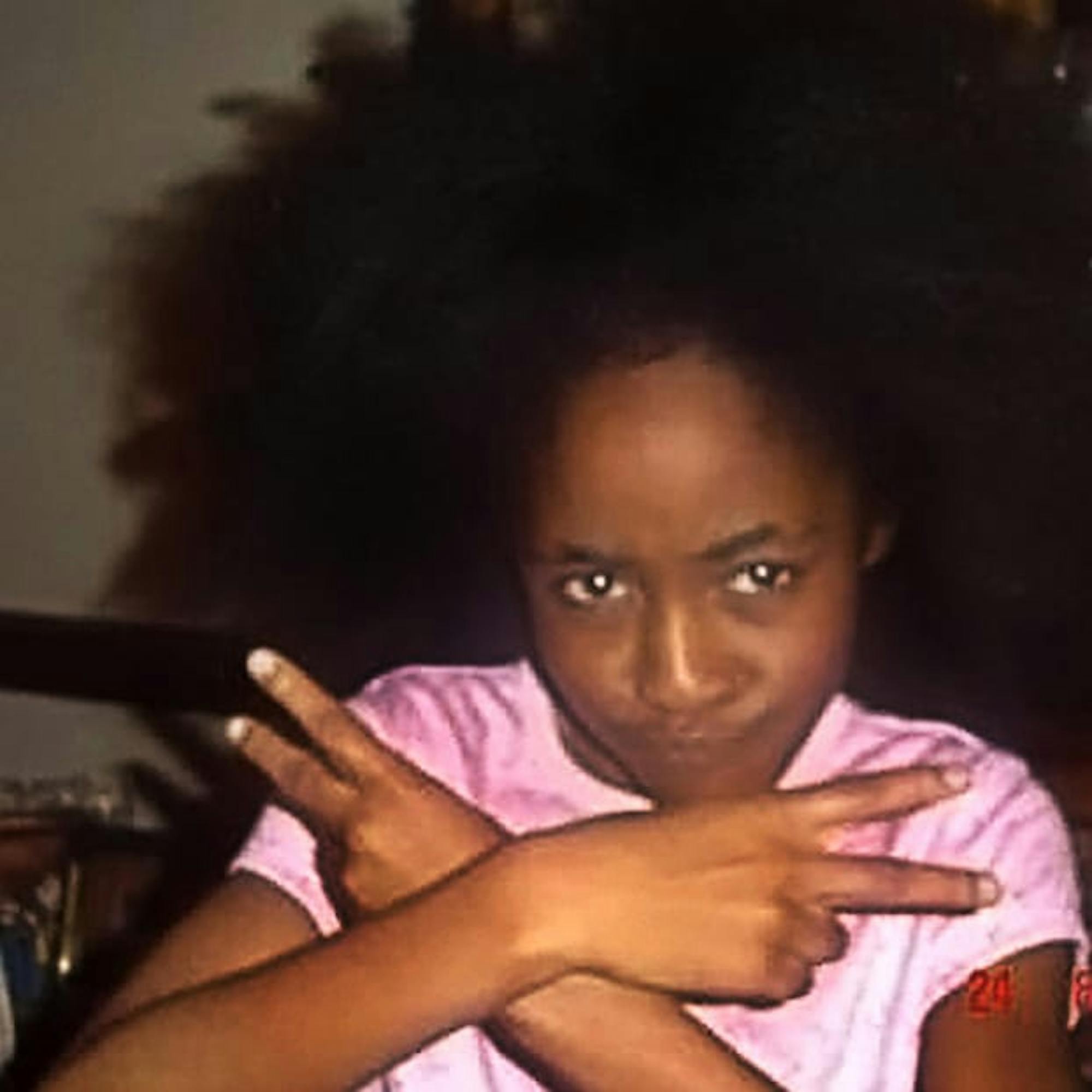 Ayo Edebiri as an adolescent, throwing up peace signs to the camera.