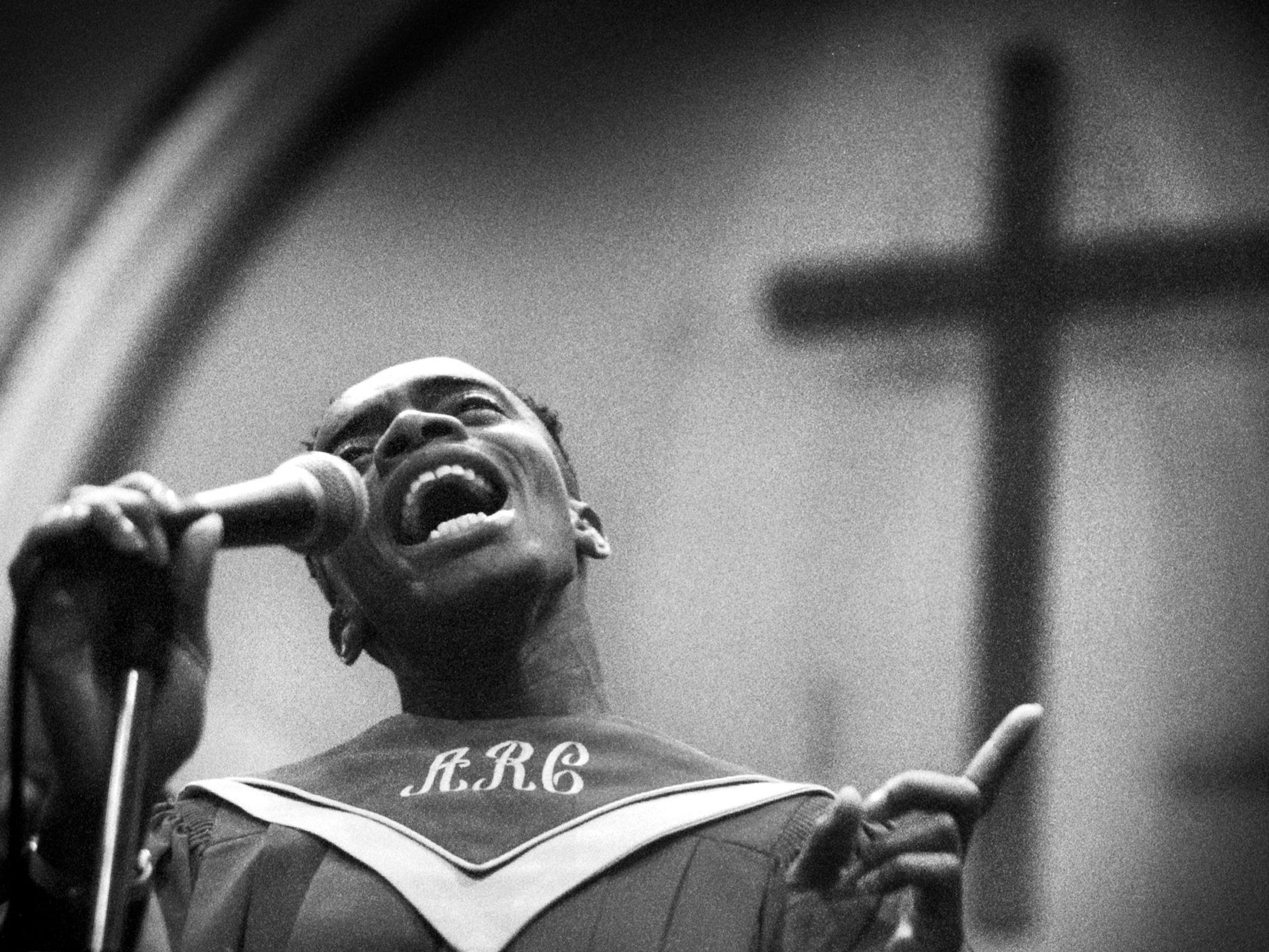 ARC choirmember Michael Paden sings a solo at AME Church in Washington D.C. He wears a gorgeously embroidered robe and sings his heart out. Behind him is a cross.