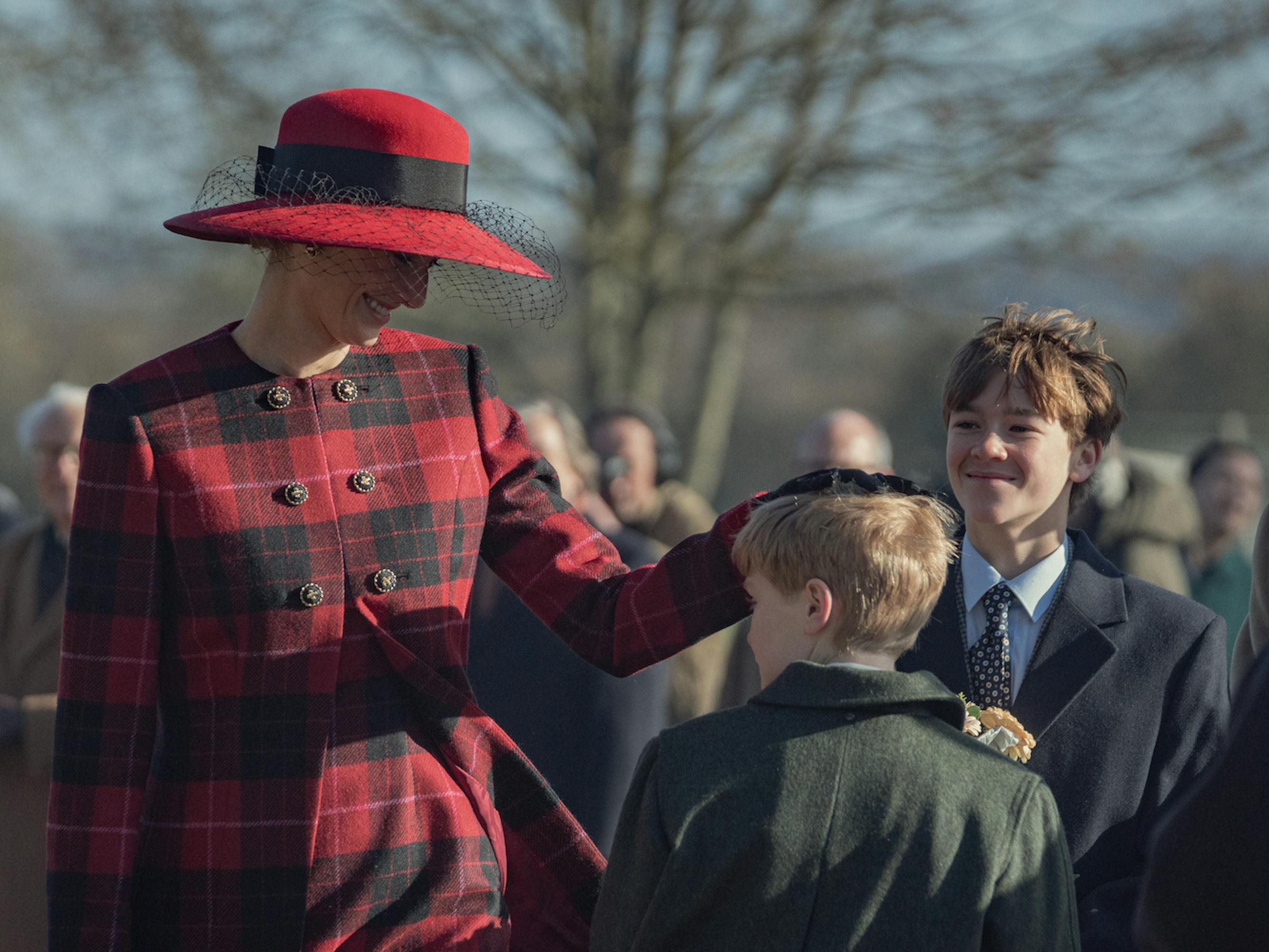 Queen Elizabeth (Imelda Staunton). Harry (Aaran Tinker), and William (Senan West) stand around the cold.