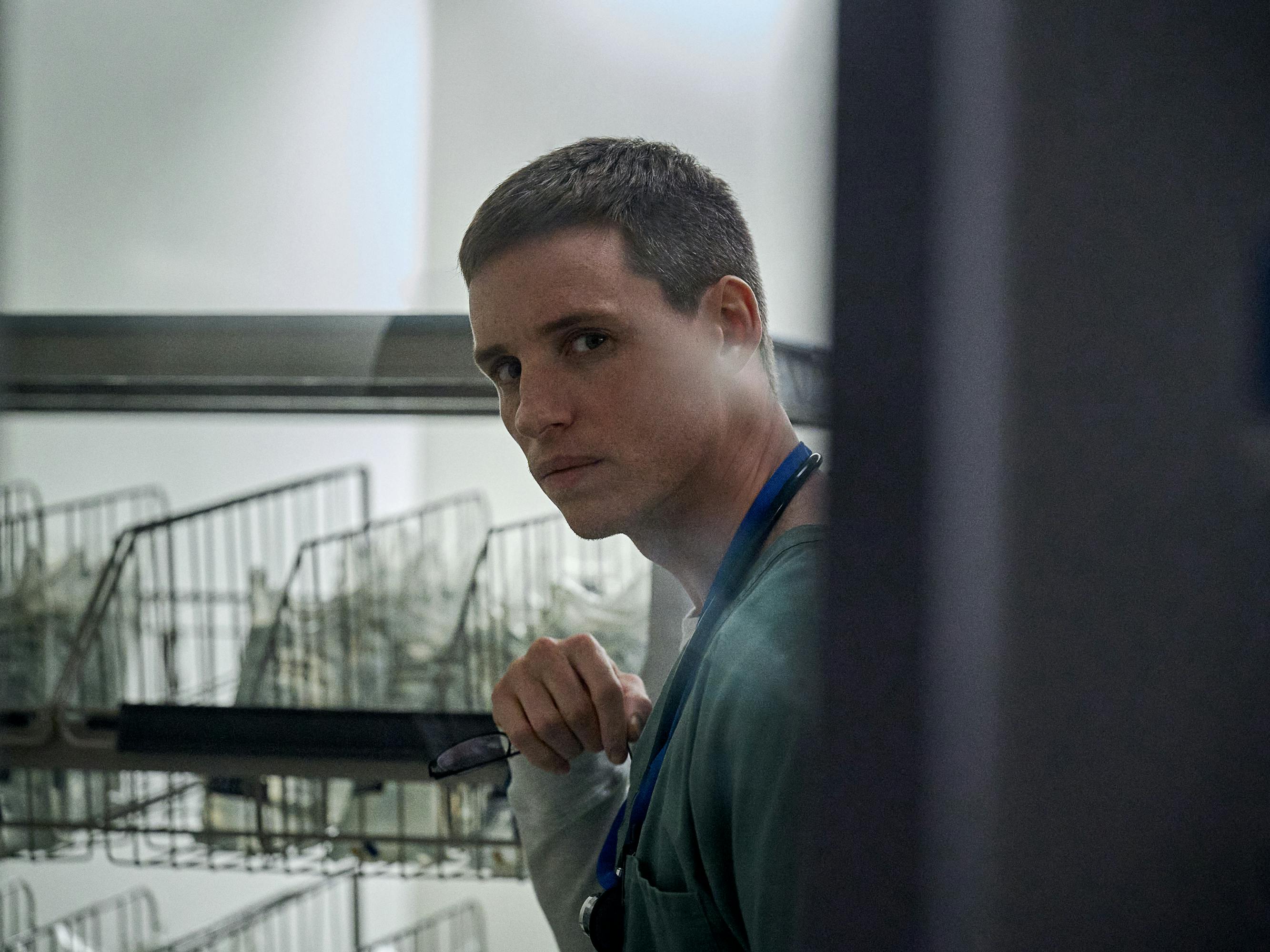 Charles Cullen (Eddie Redmayne) wears scrubs and a lanyard and walks through a storeroom.