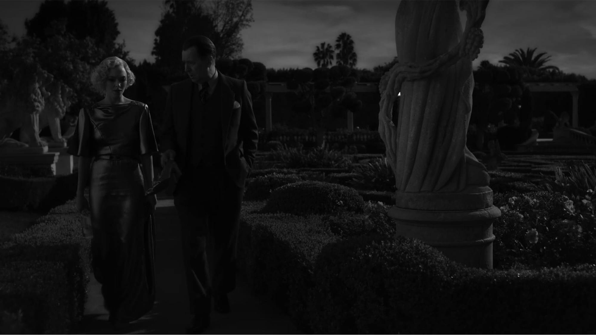 In a shot from the film, we see how the vibrant colors from the image above translate to a black-and-white experience. Light and shadow play off of Seyfriend’s shimmering dress and around statues and greenery on the grounds. 