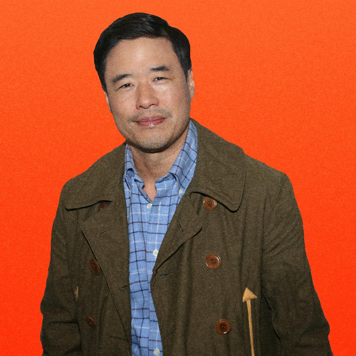 Randall Park wears a green peacoat over a blue checkered shirt. He smiles slightly against an orange background with his name written in all capital letters.