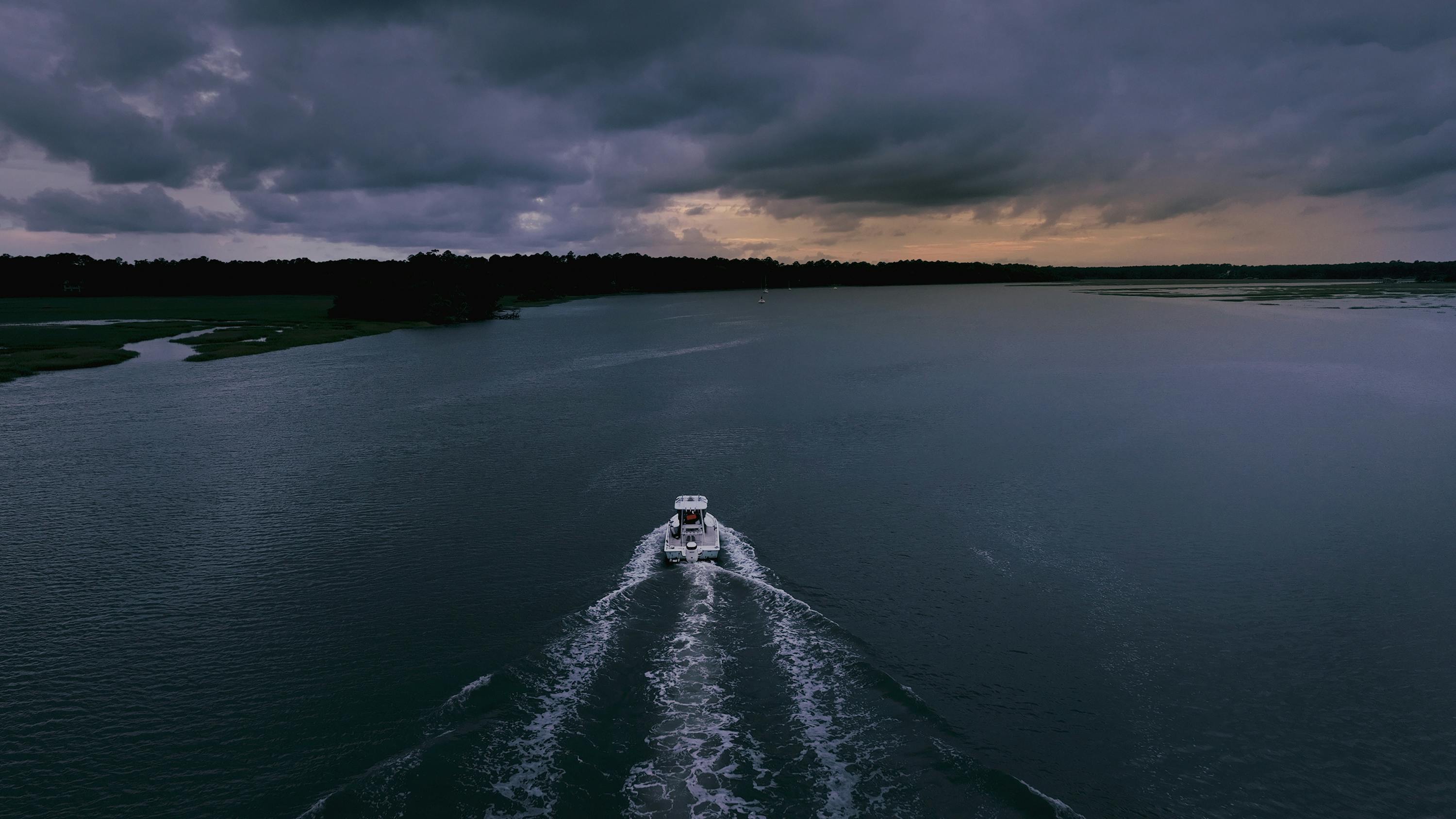 A motorboat speeds across the water under darkened skies. 