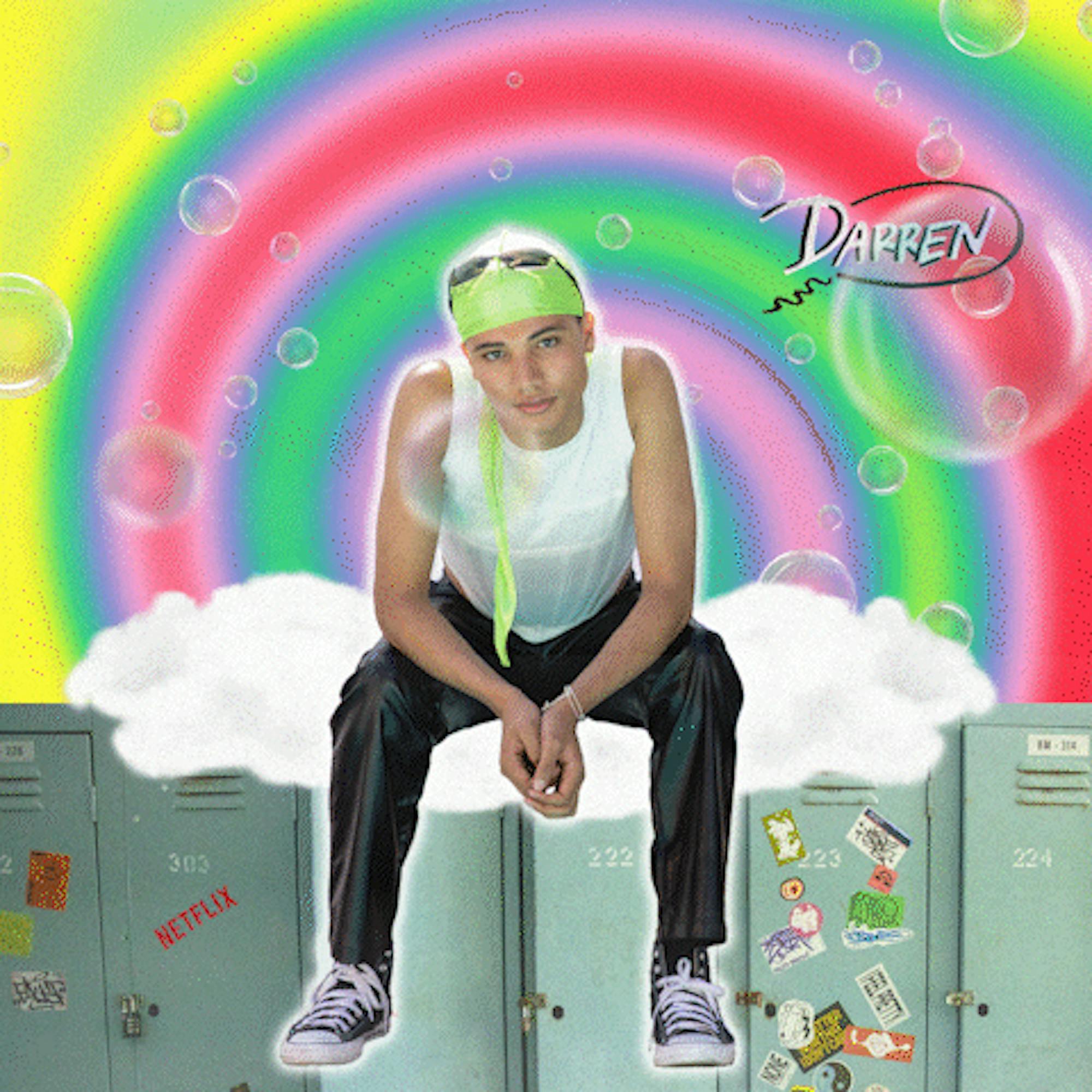 James Majoos plays Darren. Here they wear a green headscarf, white tank top, and black pants. Behind them is an animated rainbow with their name in a speech bubble to the right of their head.