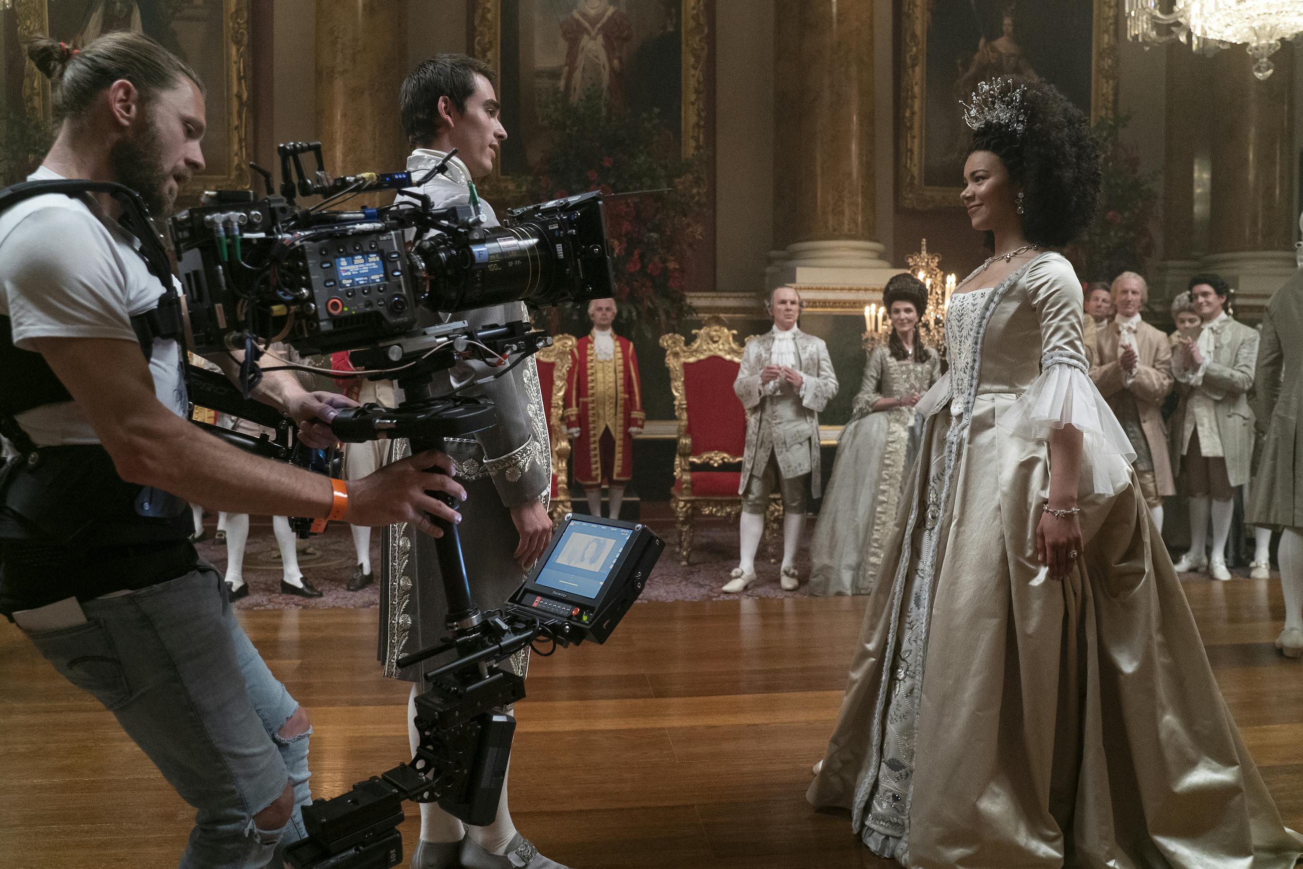 Queen Charlotte: A Bridgerton Story crew and King George (Corey Mylchreest) and Queen Charlotte (India Amarteifio) behind the scenes filming a dance sequence. 