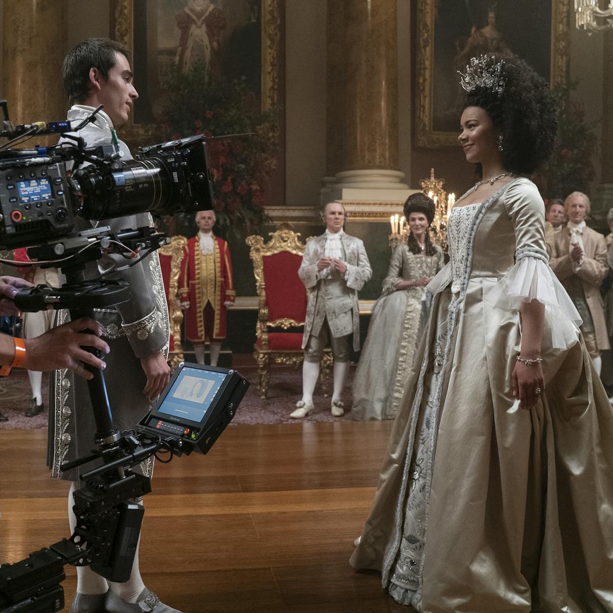 Queen Charlotte: A Bridgerton Story crew and King George (Corey Mylchreest) and Queen Charlotte (India Amarteifio) behind the scenes filming a dance sequence. 