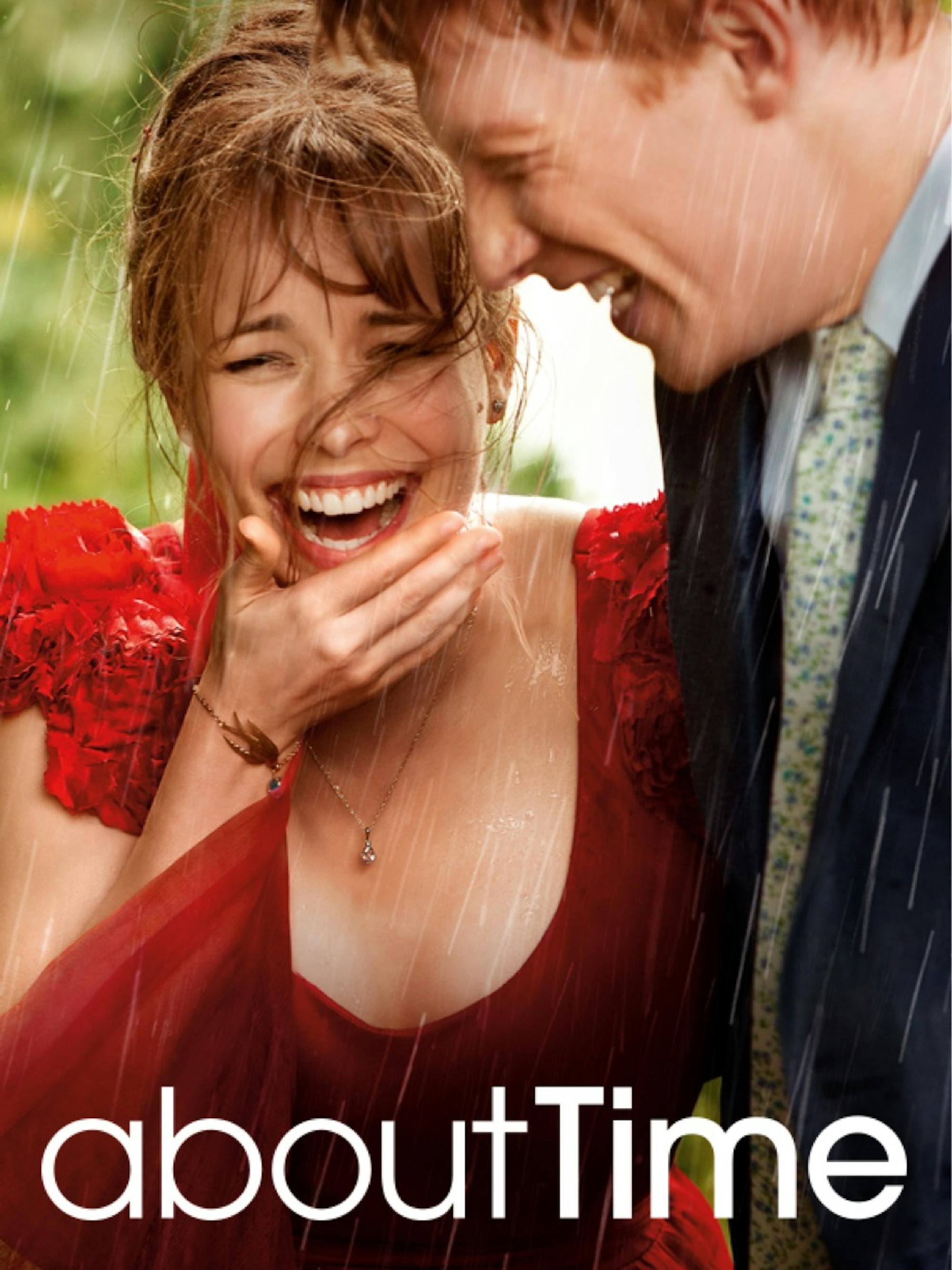 The movie poster for About Time. Rachel McAdams and Domhnall Gleeson fill the shot, smiling in the rain. McAdams wears a red gown, and Gleeson wears a suit. 