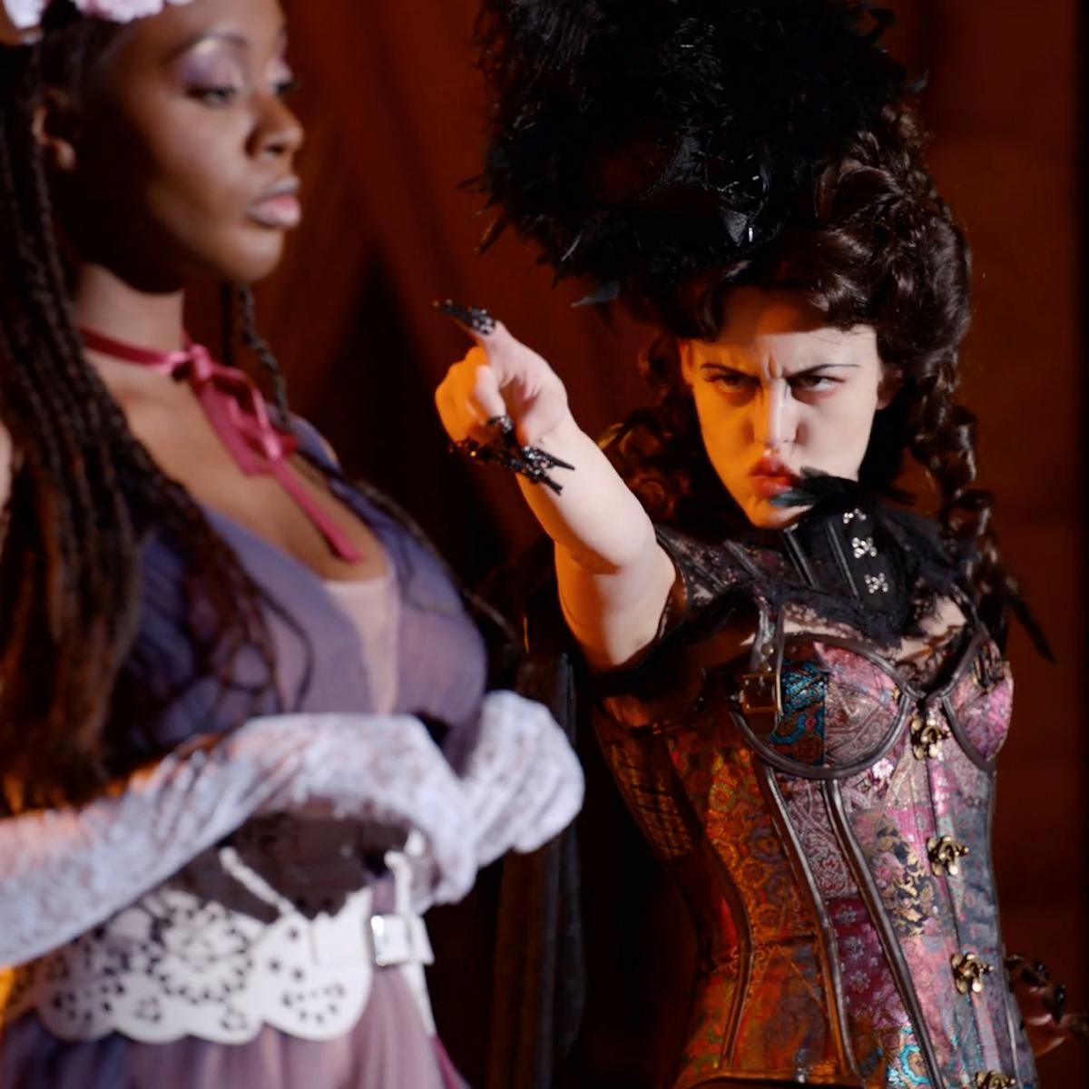 Josephine (Tameka Griffiths) and Lady Blair (Sara Waisglass) onstage. Josephine wears a red ribbon necklace and gloves. Lady Blair wears a bustier and elaborate hat.