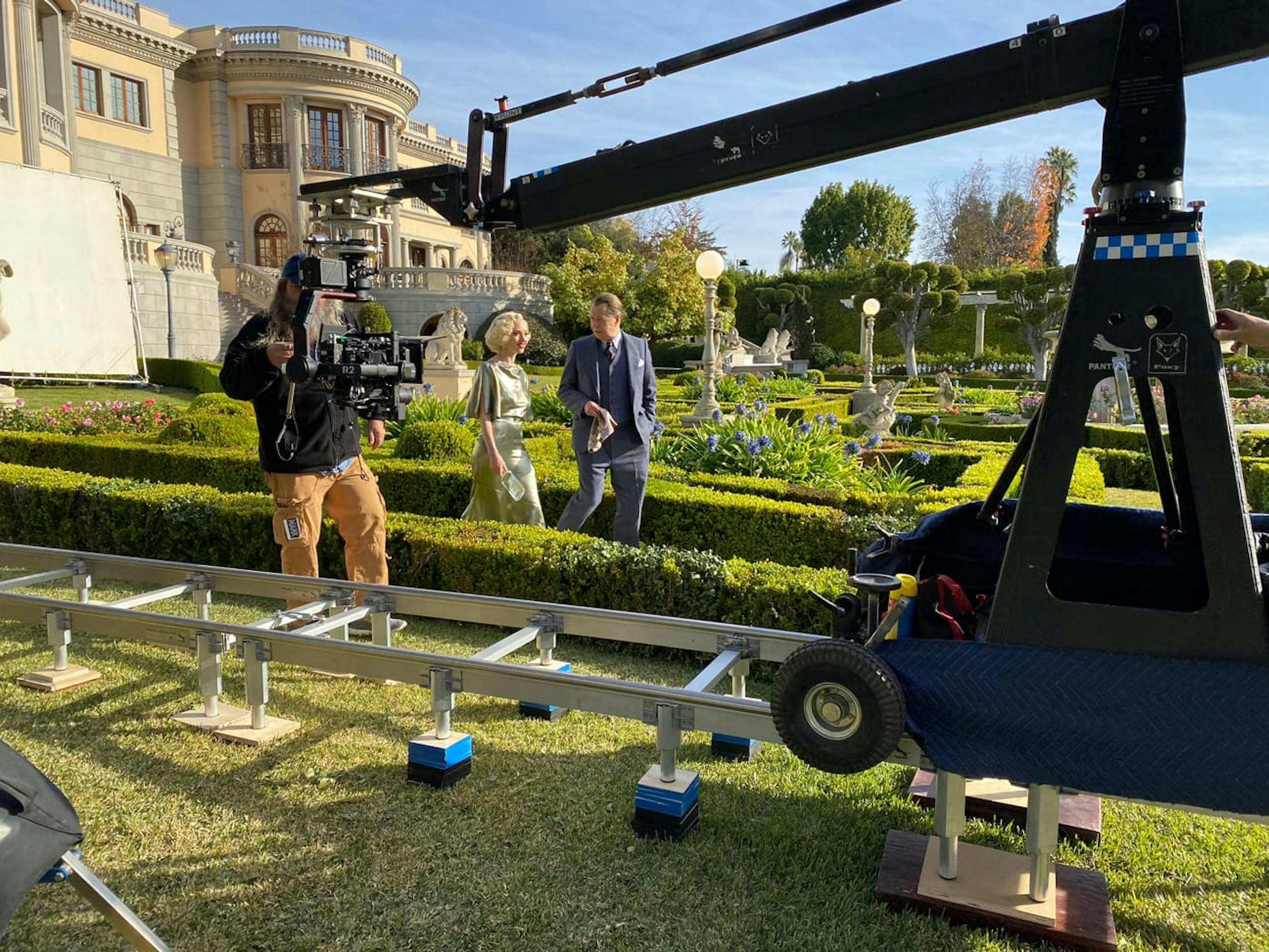 Seyfried and Oldman stroll through the bright green manicured garden that stands in for the Hearst Castle grounds.