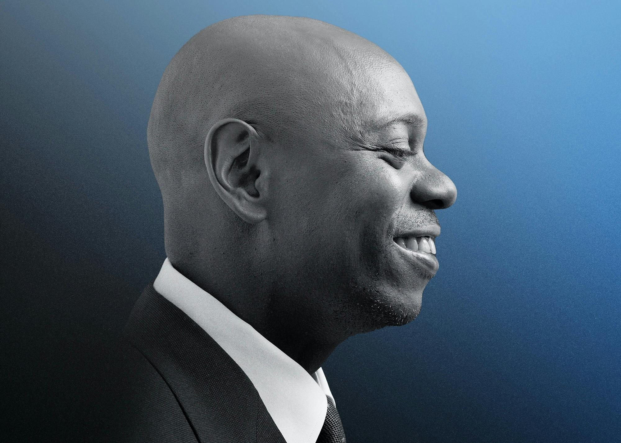 A profile shot of Dave Chappelle smiling. He wears a dark suit and white shirt, and the background is a navy gradient.