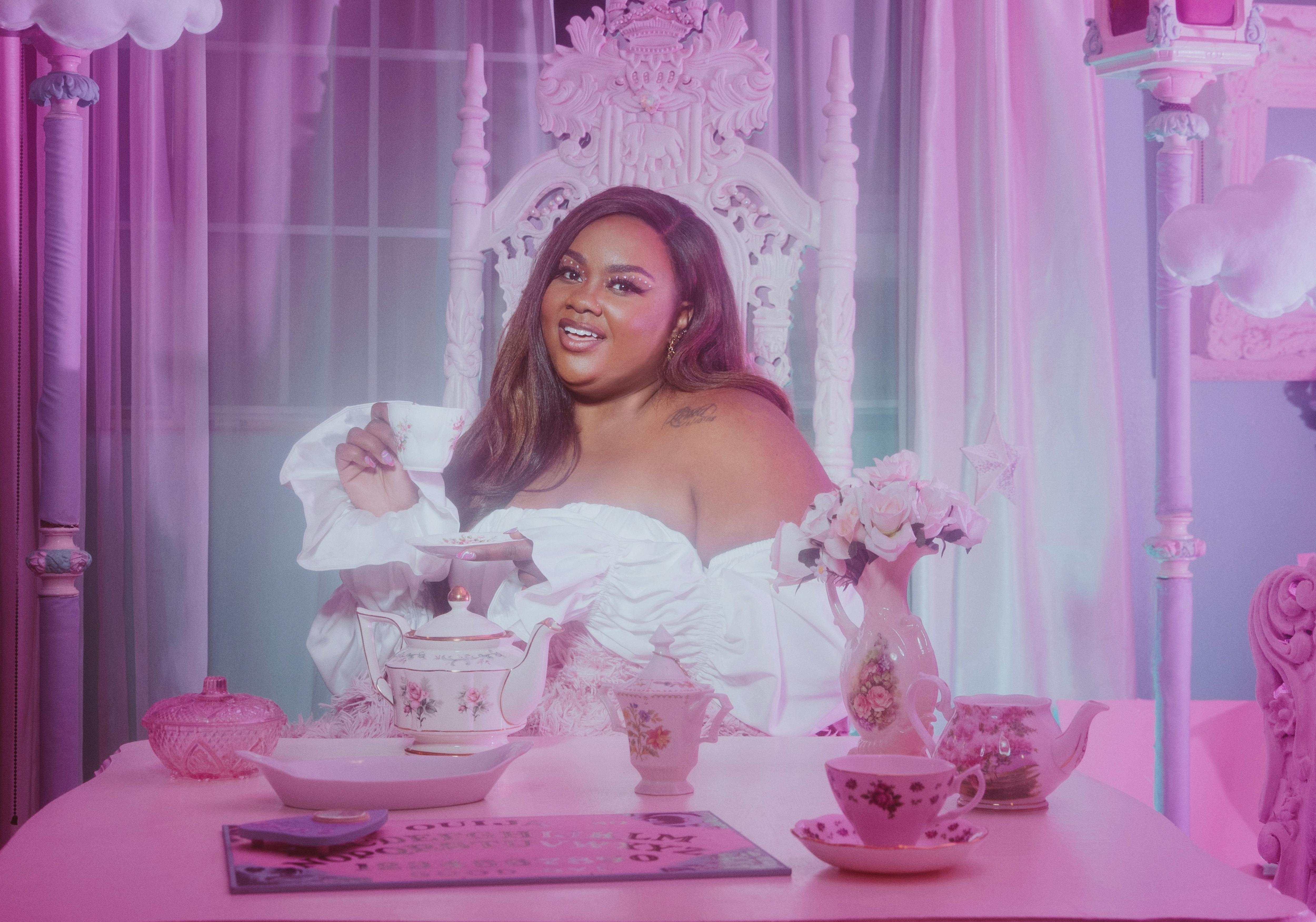 Nicole Byer looks positively ethereal in a white dress in this pink and blue gauzy shot.