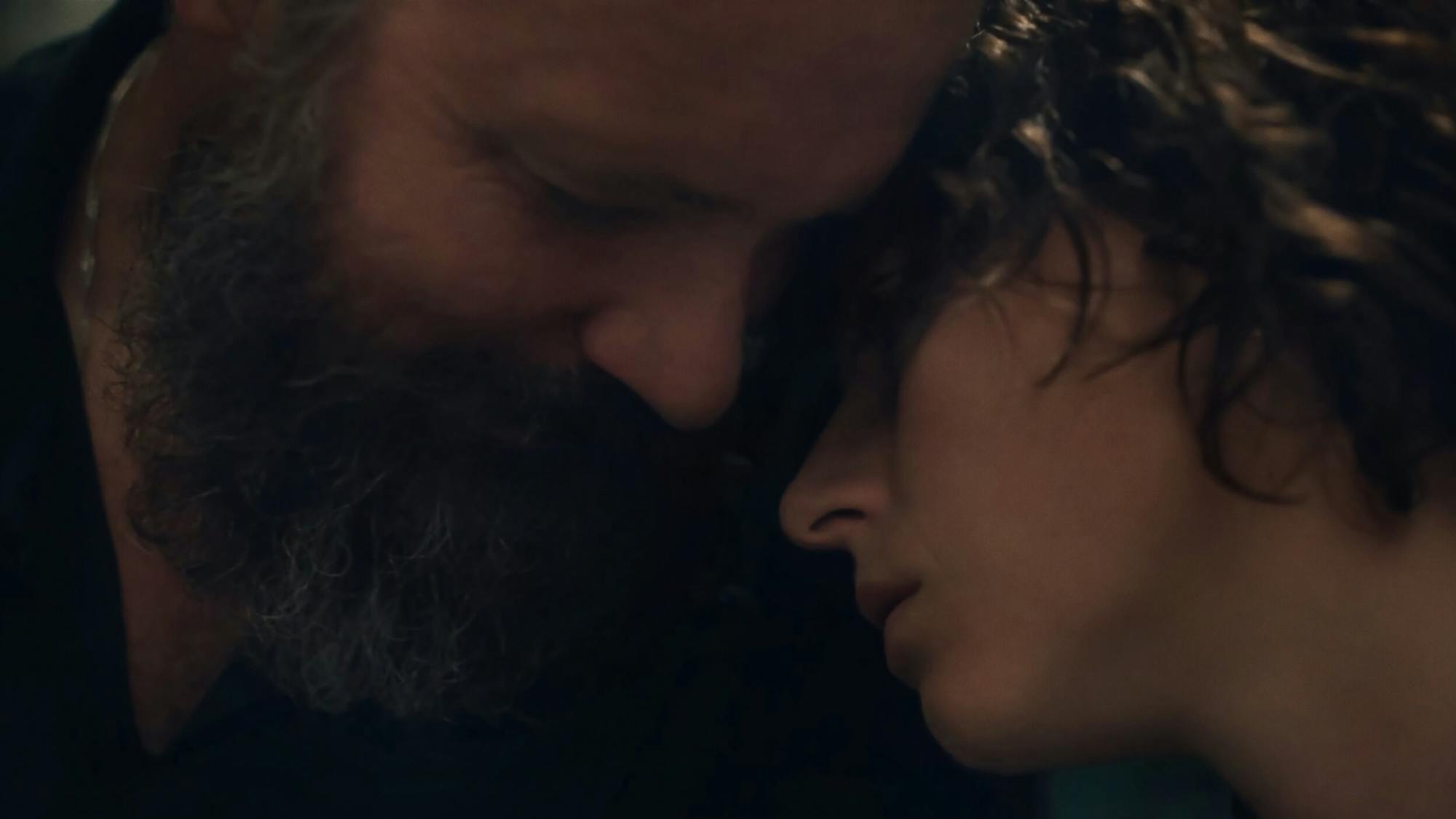 Professor Hardy (Peter Sarsgaard) and Yound Leda (Jessie Buckley) embrace in this close-up shot.