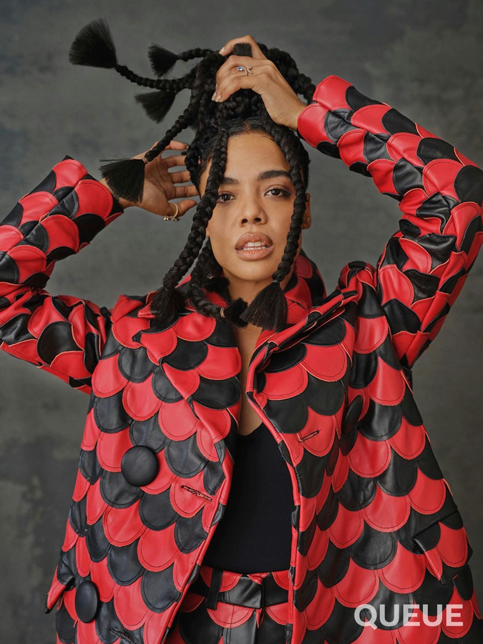 Tessa Thompson wears a red and black scalloped jacket and matching pants.