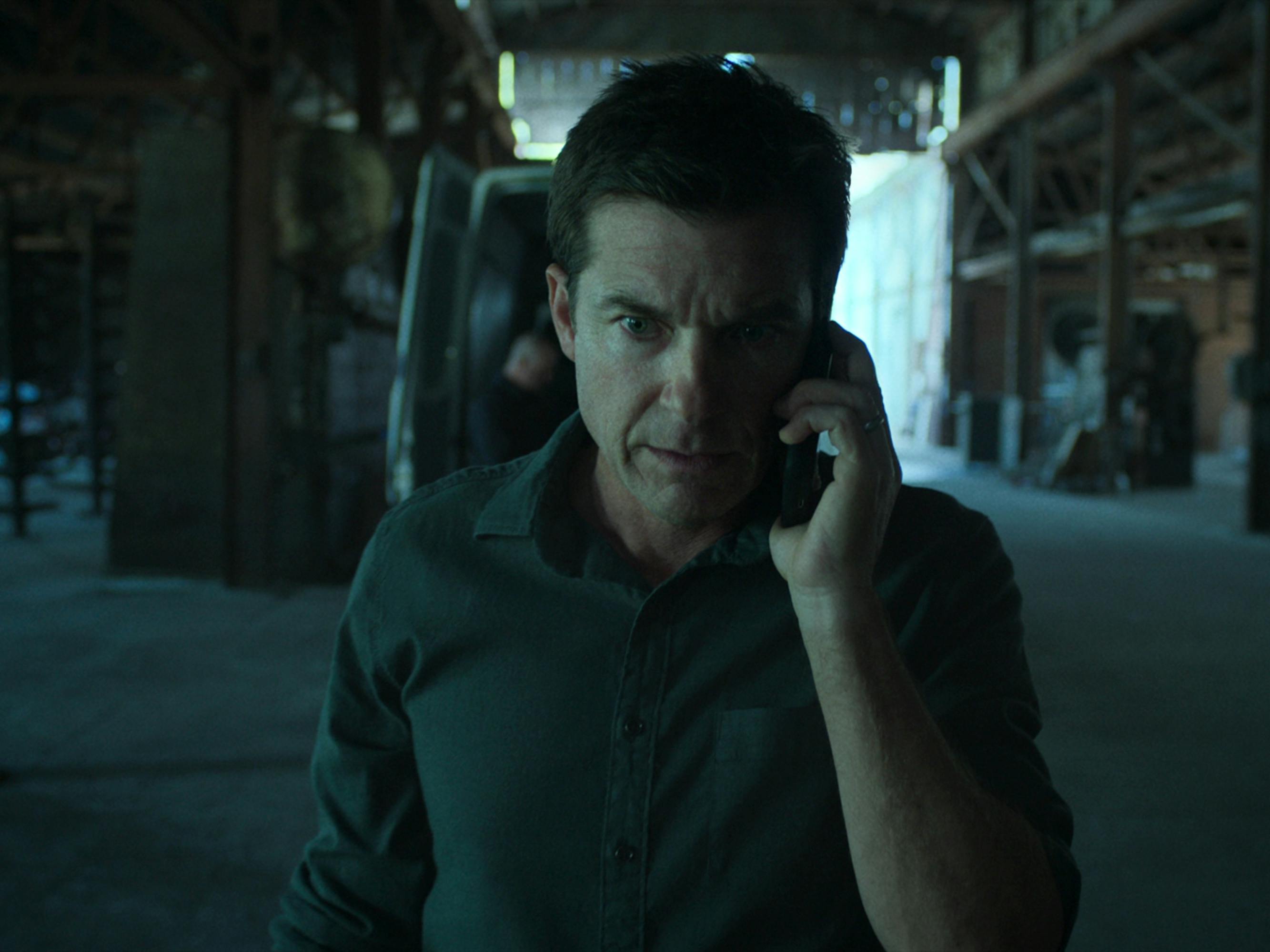 Jason Bateman talks on the phone with an urgent expression.
