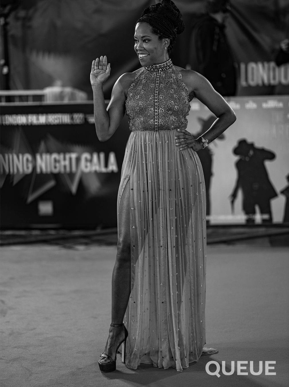 Regina King in an embellished halter-neck gown with thigh-high split waves to the crowd on the red carpet