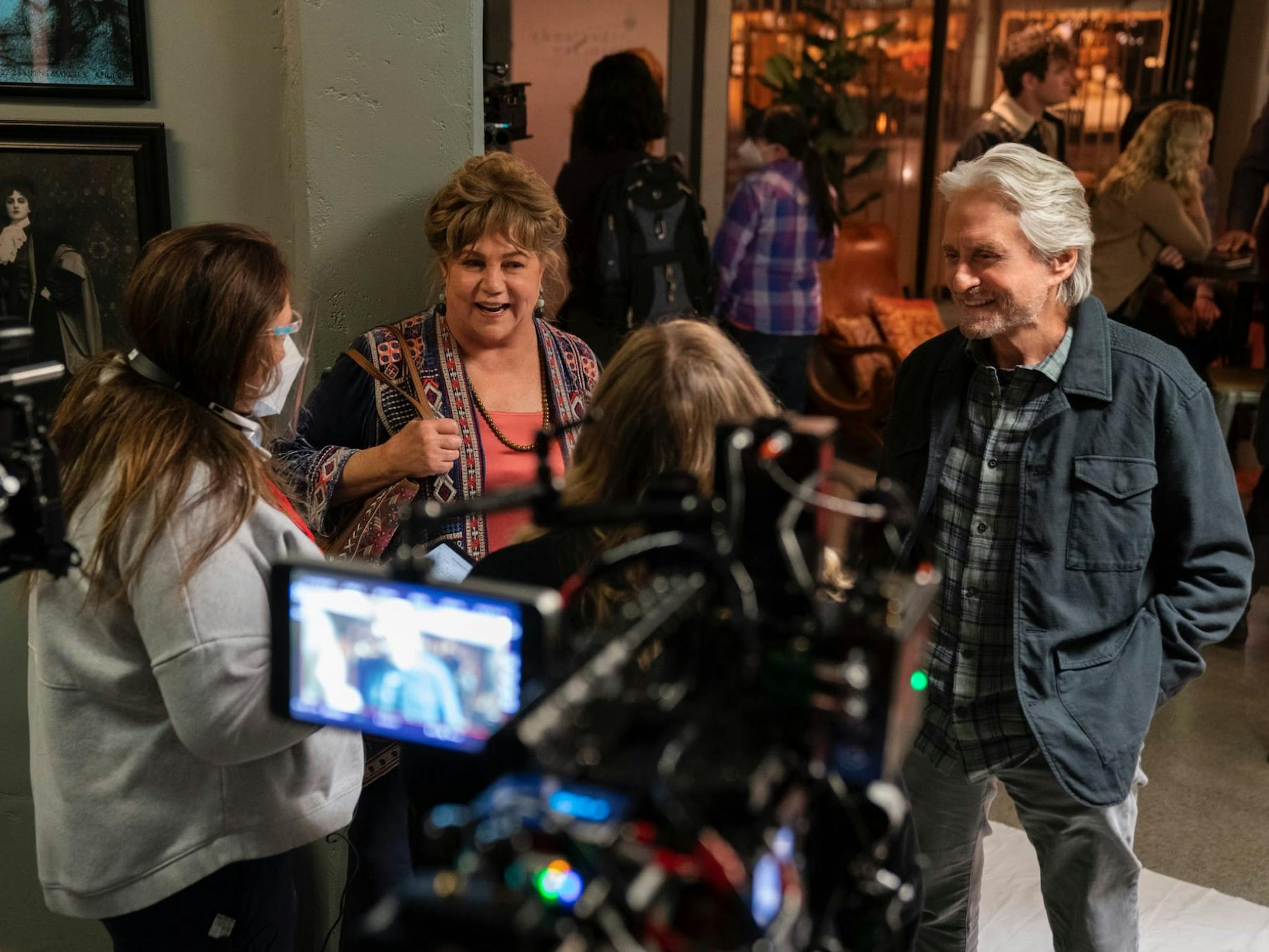 Kathleen Turner, Michael Douglas, and The Kominsky Method crew stand around and laugh, with camera rigs surrounding them.