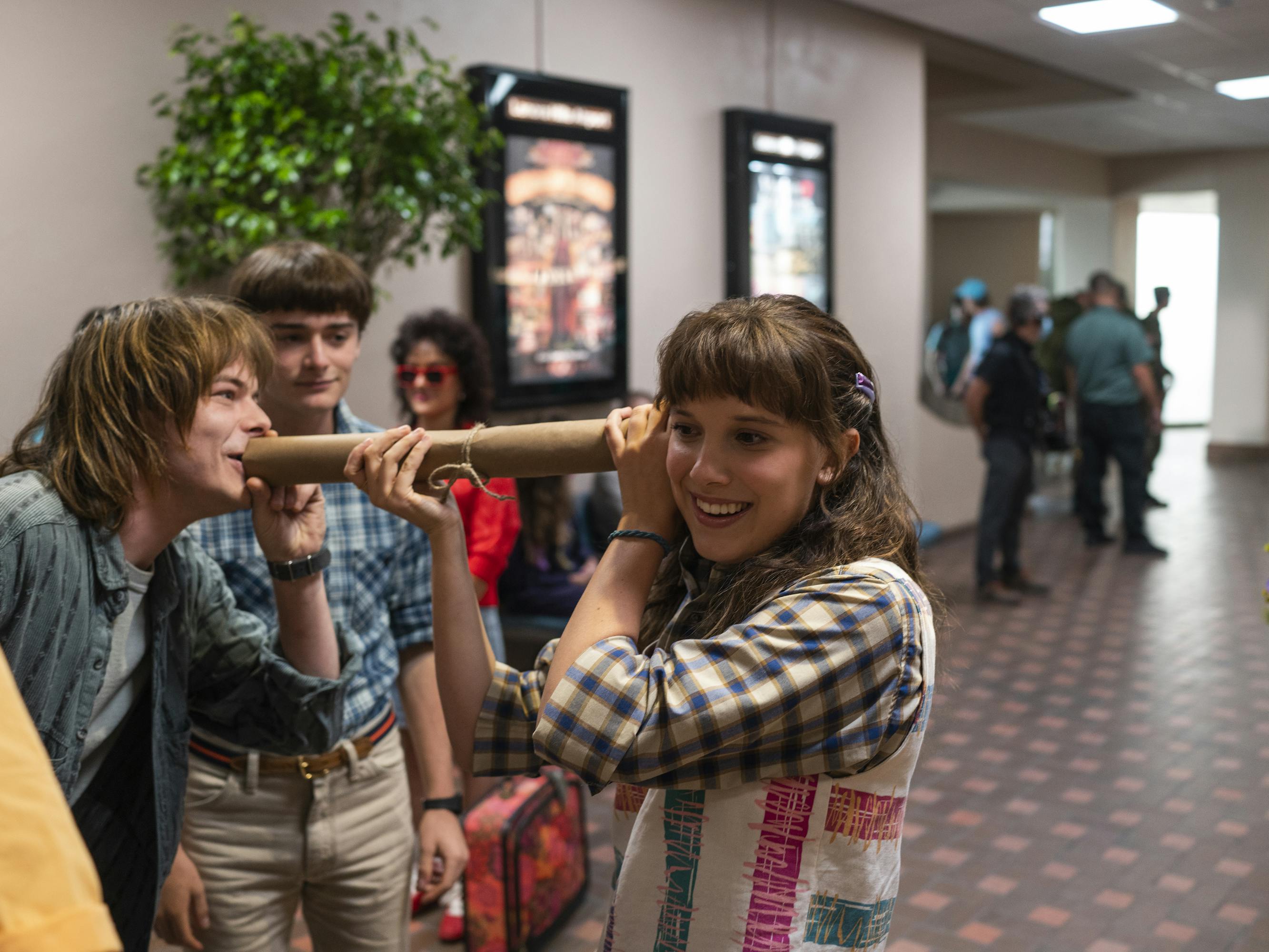 Jonathan Byers (Charlie Heaton), Will Byers (Noah Schnapp), and Eleven (Millie Bobby Brown) goof off in a movie theater.