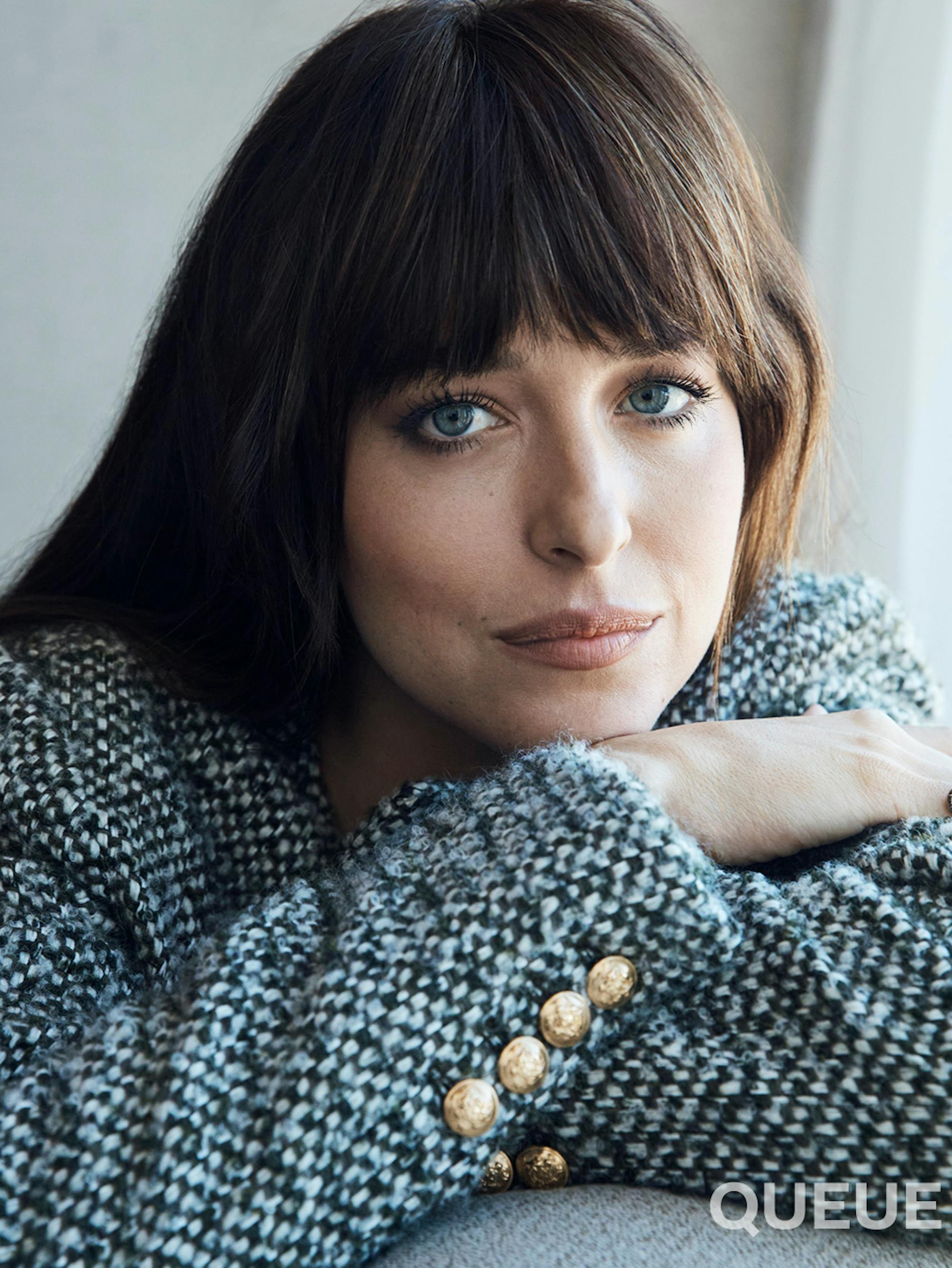 Dakota Johnson wears a knit jacket with gold buttons. 