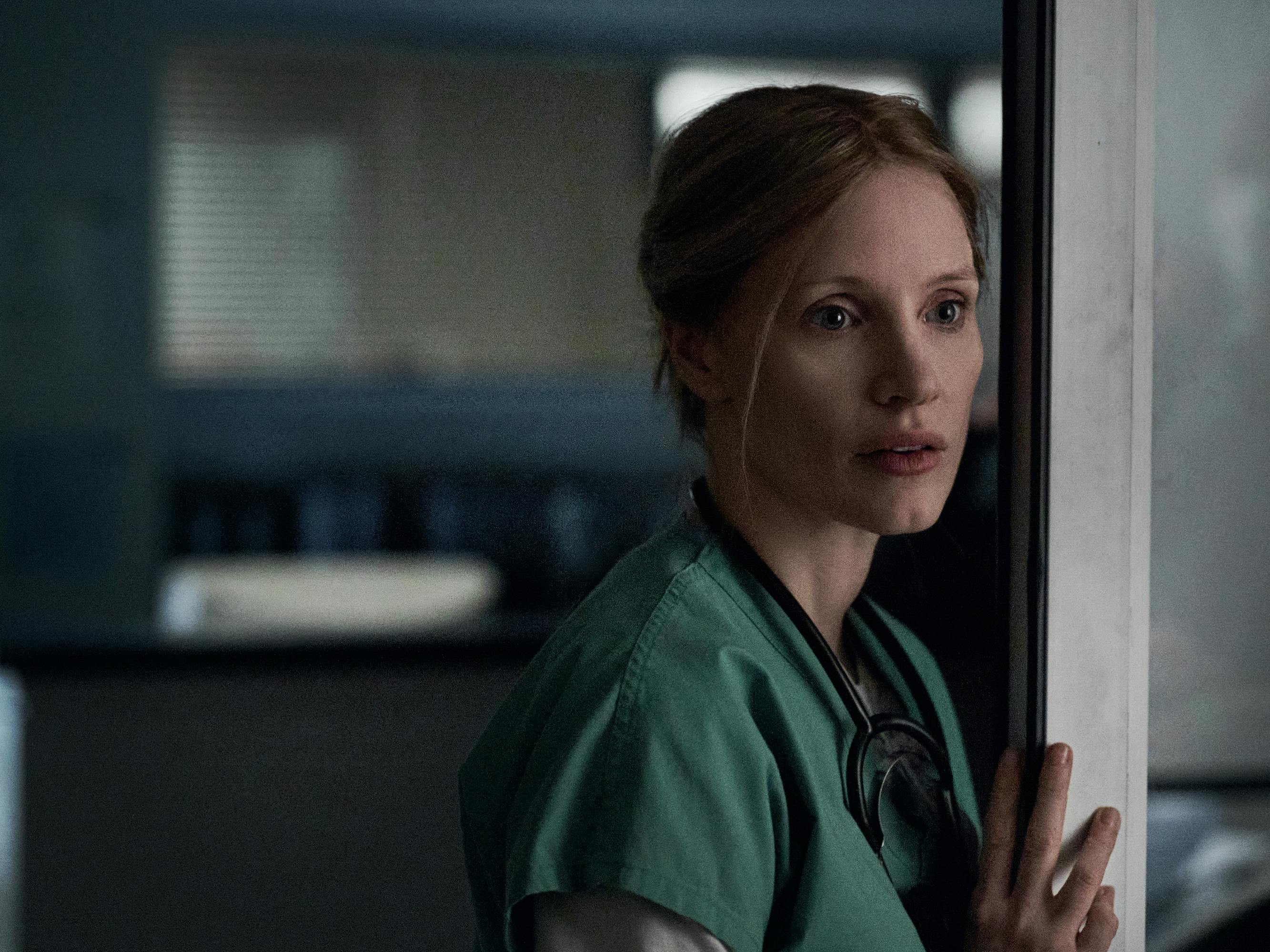 Amy Loughren (Jessica Chastain) wears scrubs and leans against a hospital wall.