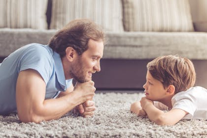 Father and son laying on the floor looking at each other