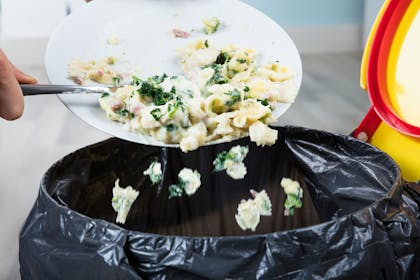 Food waste being scraped into the rubbish bin