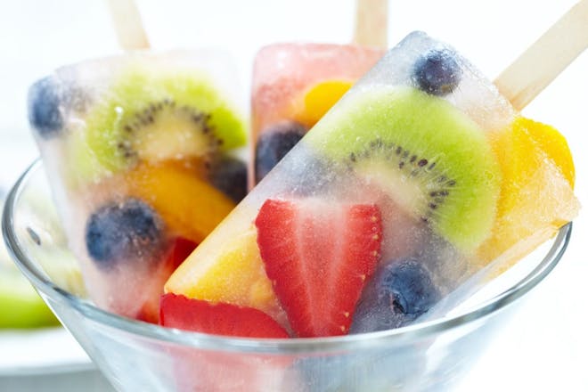 Glass bowl of frozen fruit lollies made with strawberries, blueberries and kiwi