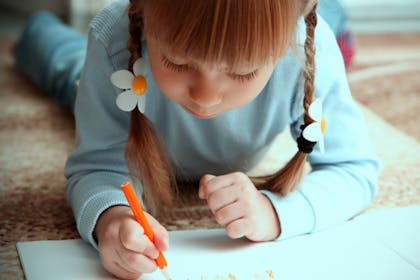 Girl lying on floor drawing a picture