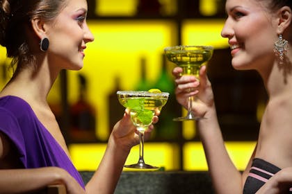 two women drinking cocktails at bar
