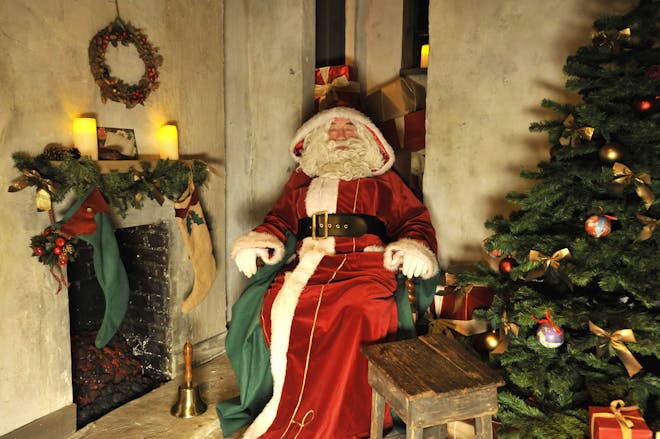 Santa in grotto with Christmas tree and fireplace