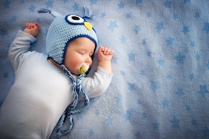 Baby in owl hat sleeping on back
