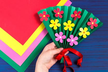 Handmade paper fan craft with paper flowers glued on 