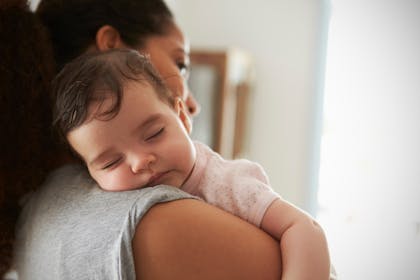 woman holding baby sleeping on her shoulder