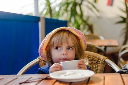 girl wearing hat drinking from tea cup